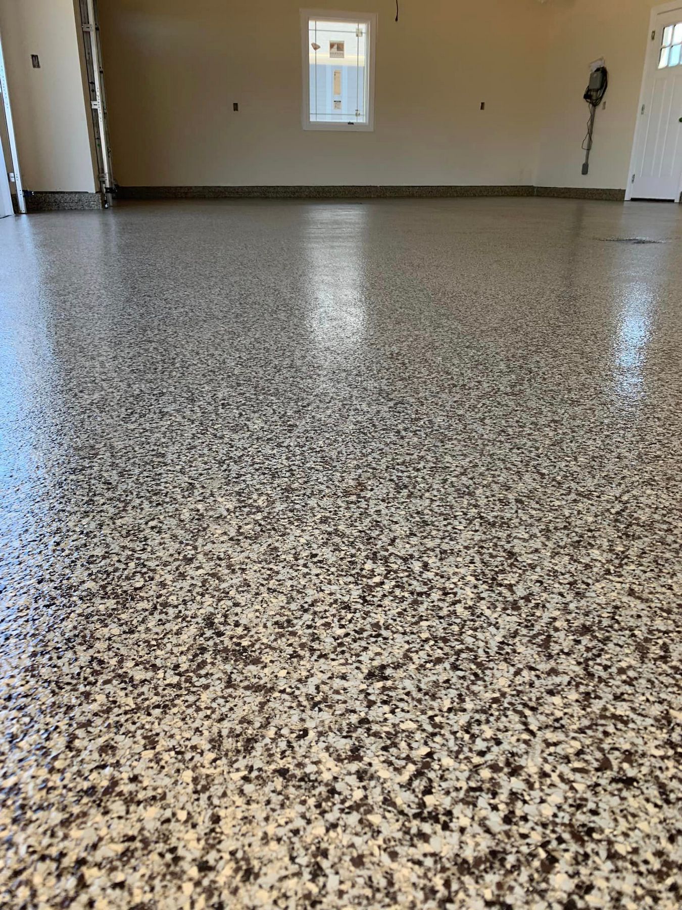 Empty room with speckled epoxy floor and a small window on the far wall