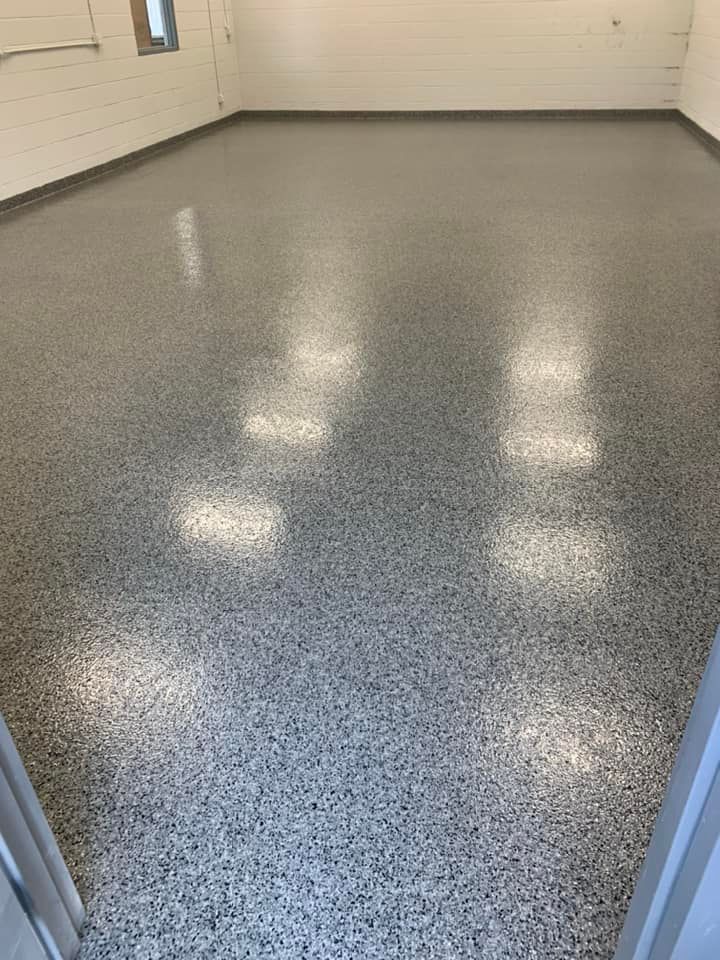 Empty room with glossy speckled epoxy floor and white walls, viewed through a doorway