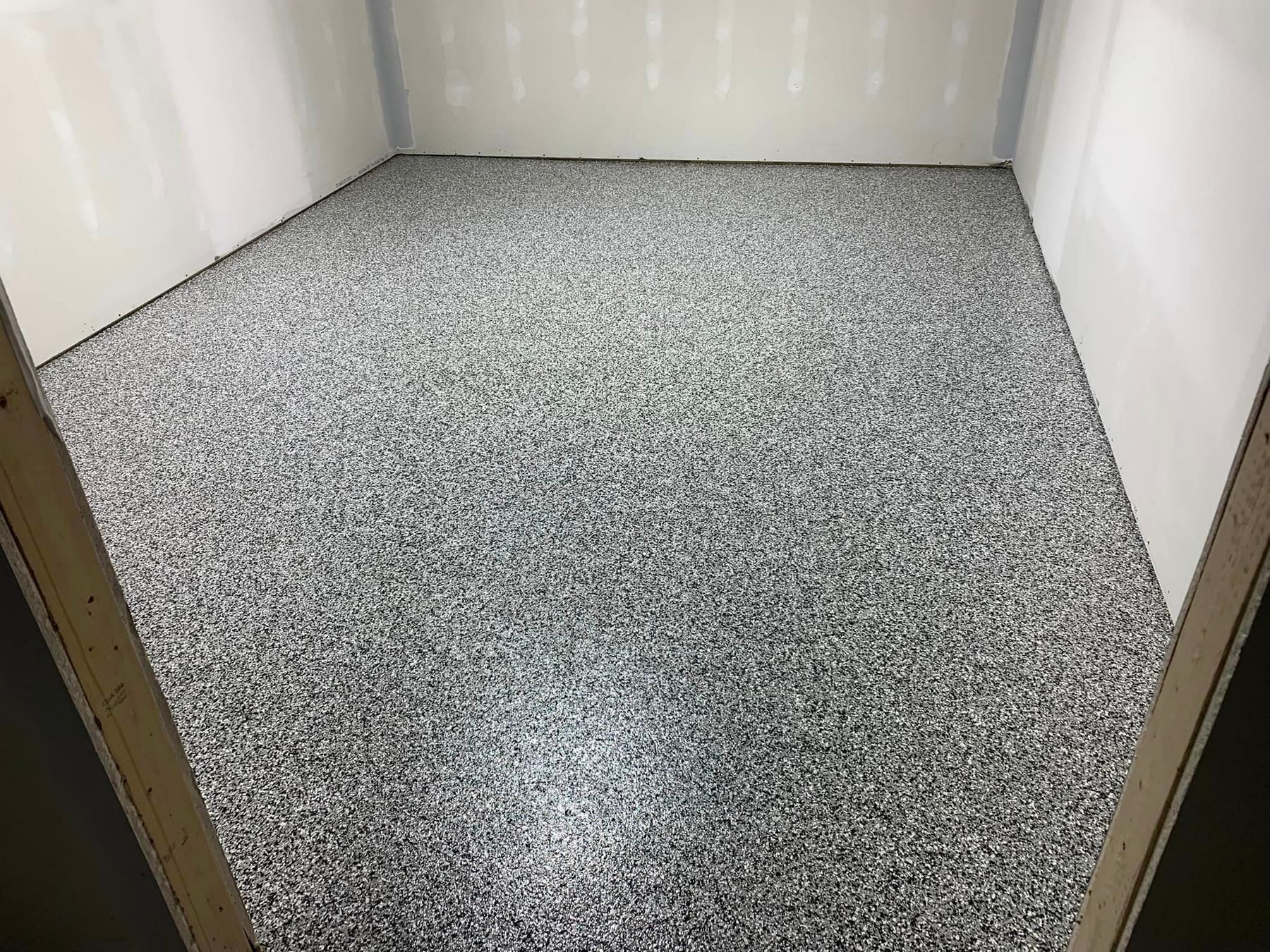 Empty white storage closet with speckled gray floor.