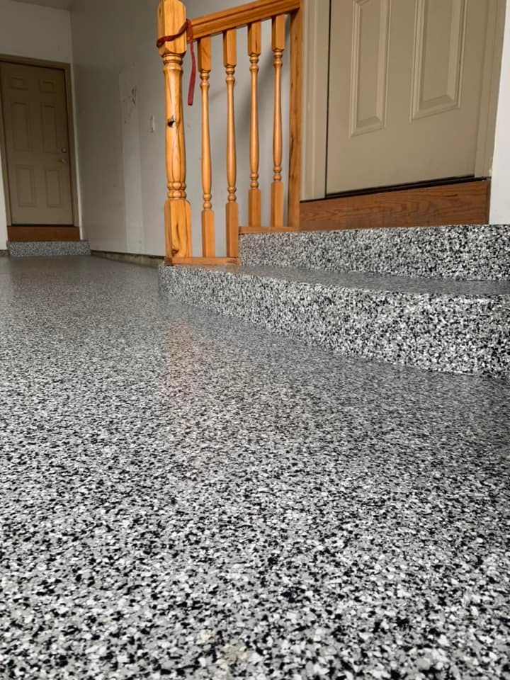 Speckled gray floor with a wooden stair railing and beige doors in a home interior