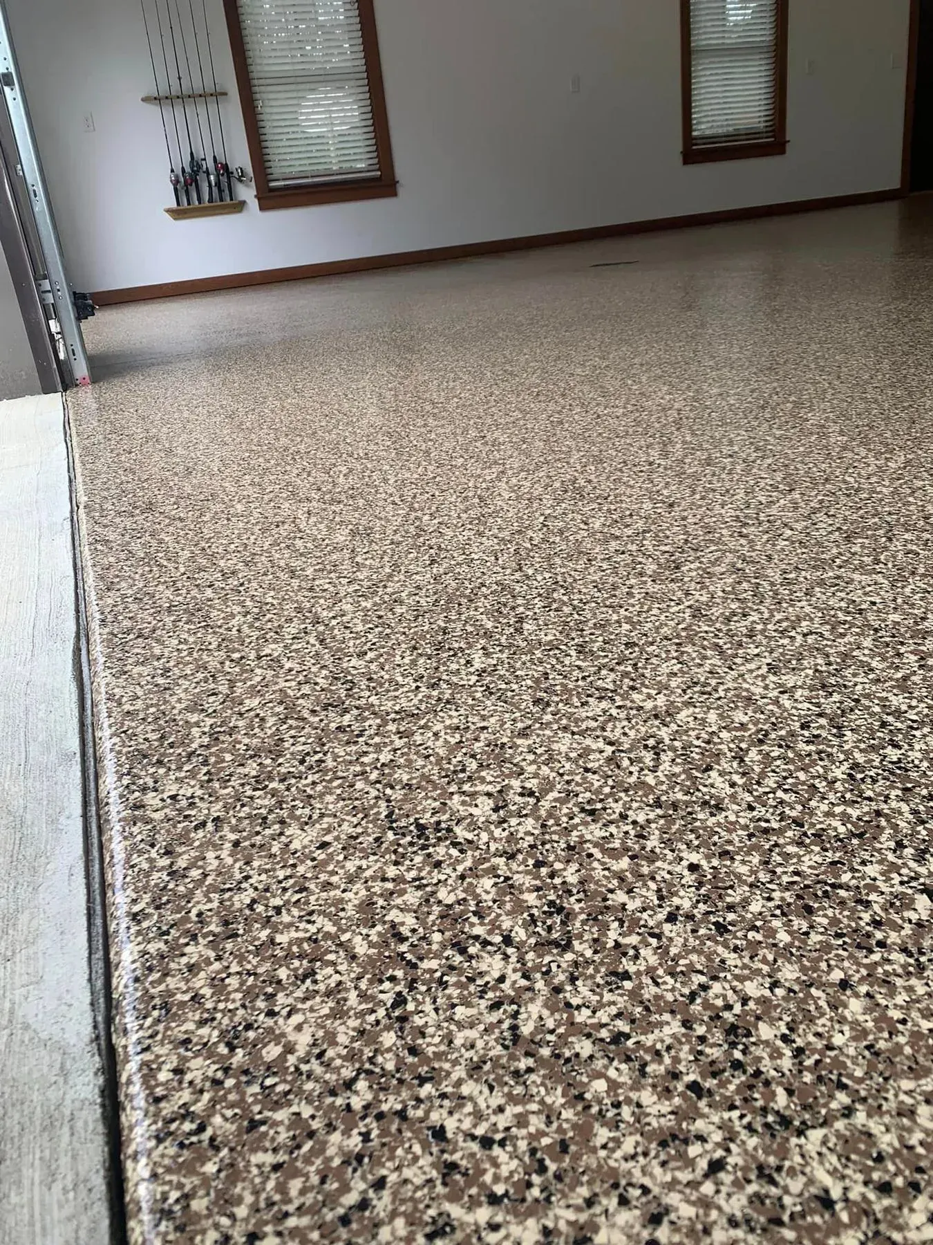 Empty speckled floor in a plain indoor room with windows on the far wall