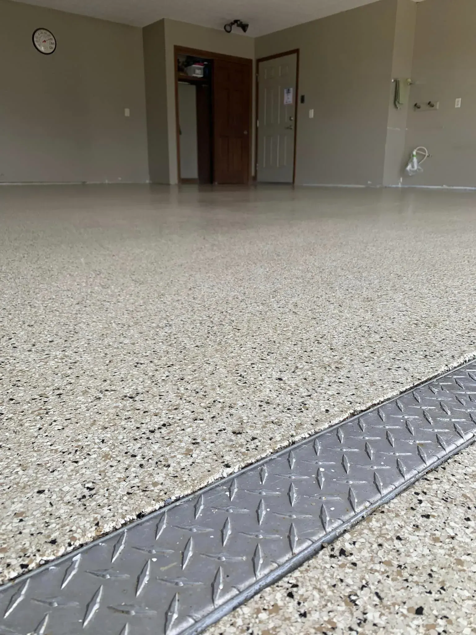 Empty indoor room with speckled floor and metal threshold strip, viewed low to the ground.