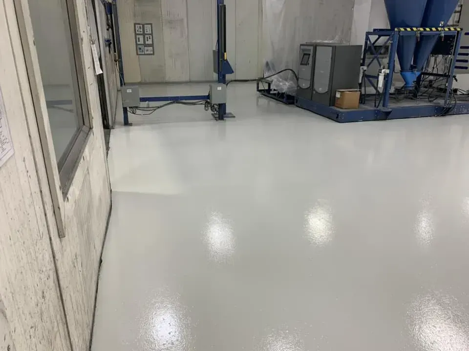 Industrial room with glossy white floor, metal equipment, and large machinery along the walls