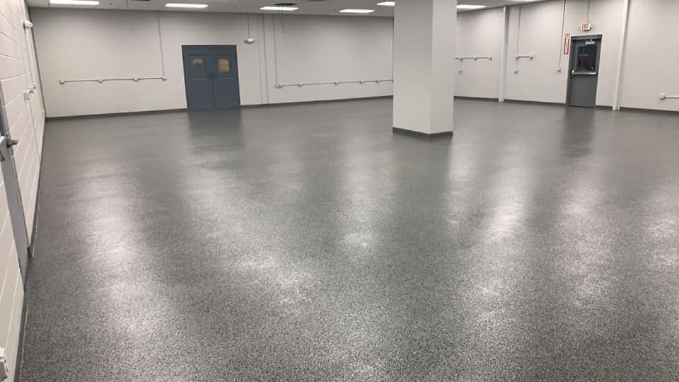 Empty gray room with polished floor, white walls, columns, and blue doors.