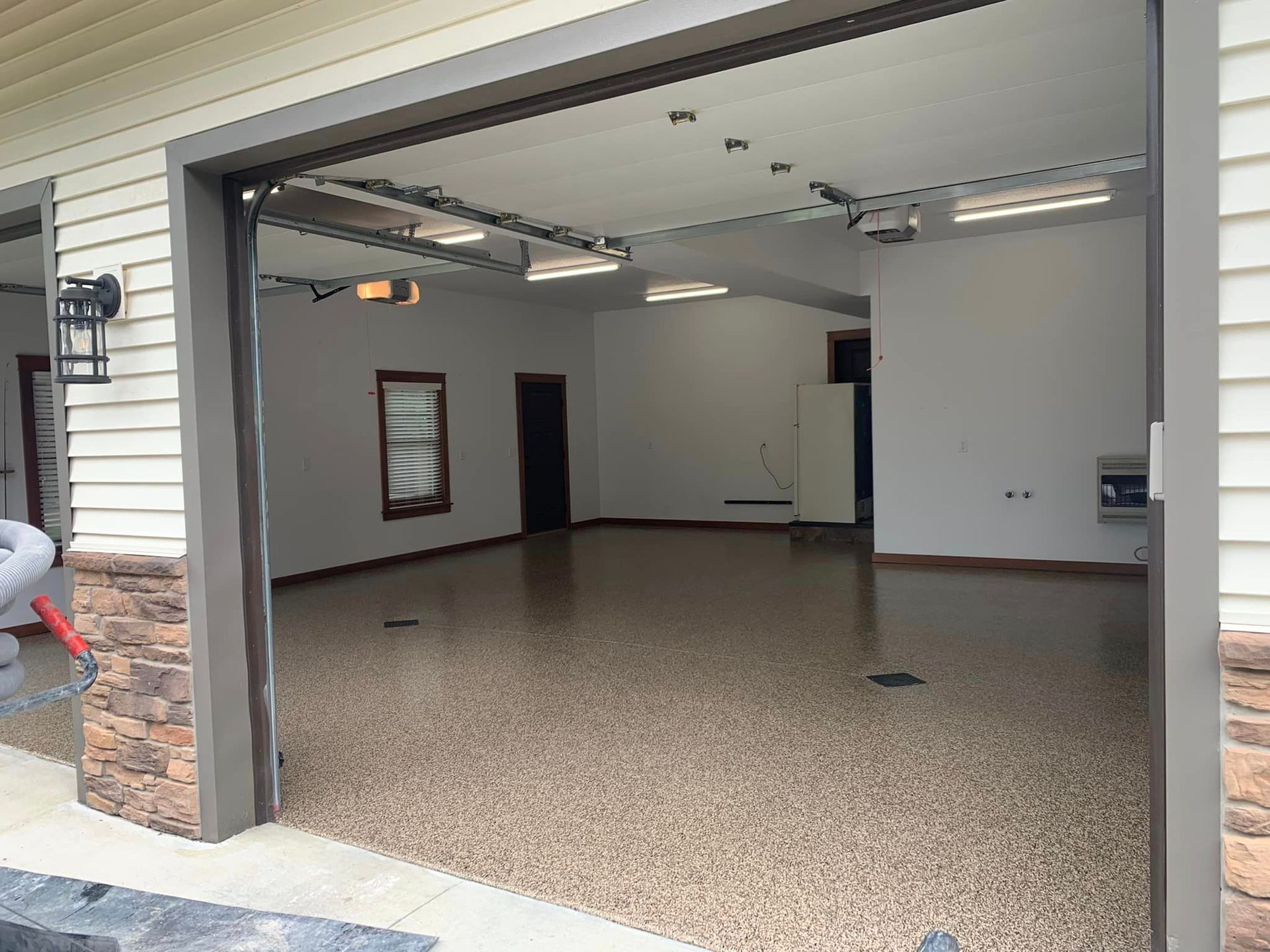 Open garage with speckled floor and white walls, viewed from the driveway.