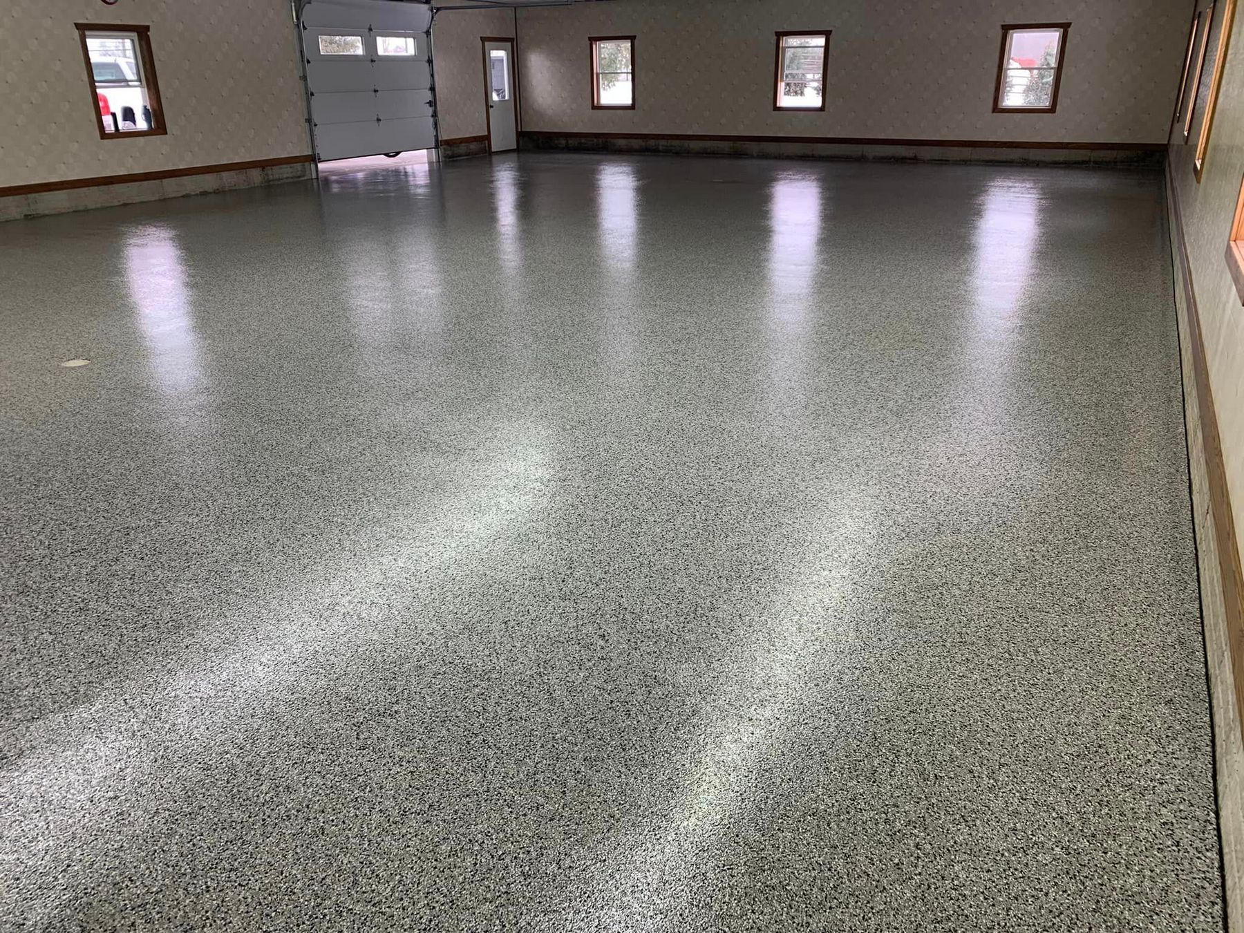 Empty indoor room with gray speckled floor and small windows along the walls