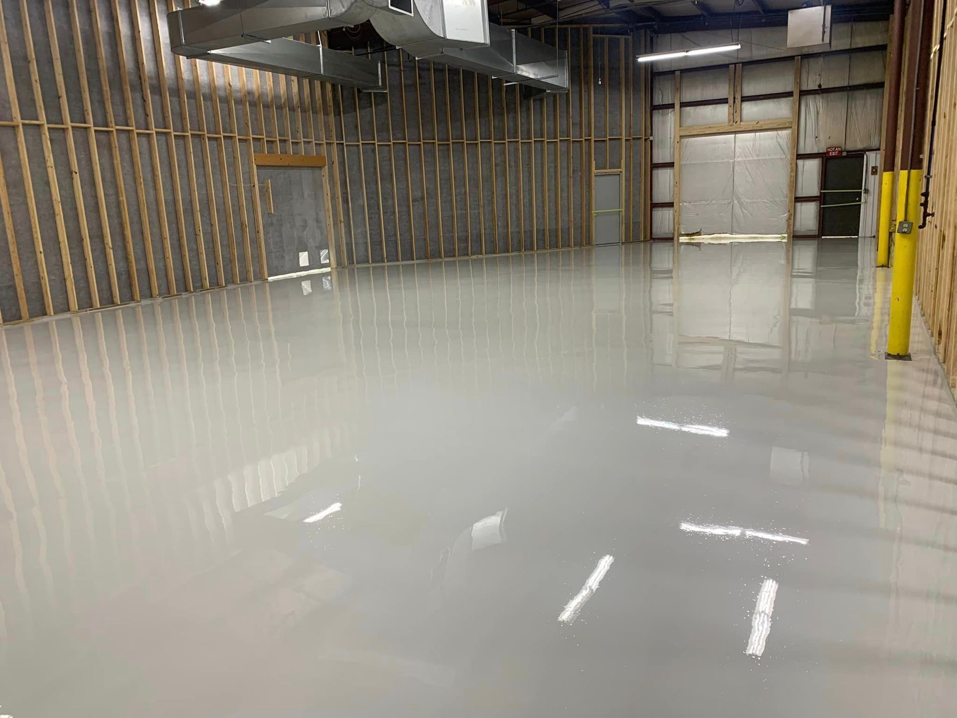Empty warehouse interior with glossy white floor and exposed wall framing