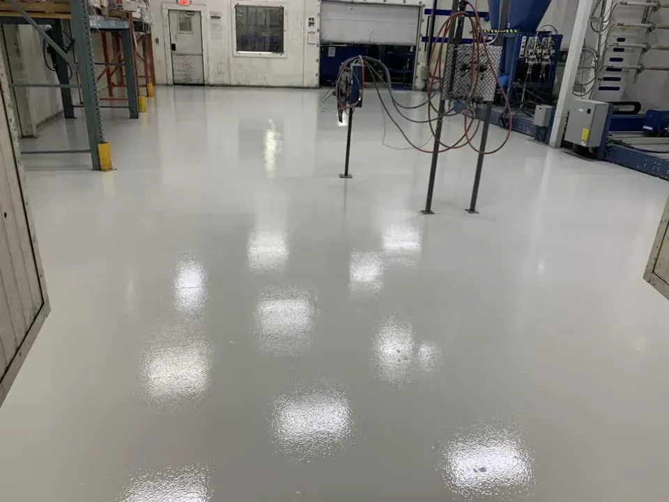 Empty glossy factory floor with metal equipment and cables in the background