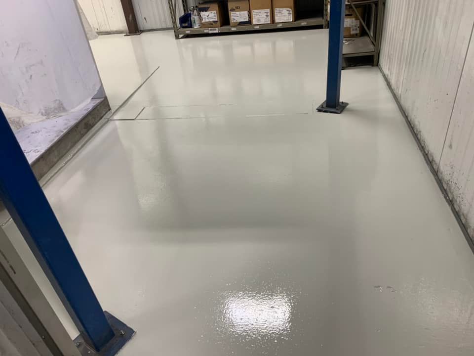 Glossy white warehouse floor between blue support columns and storage shelves