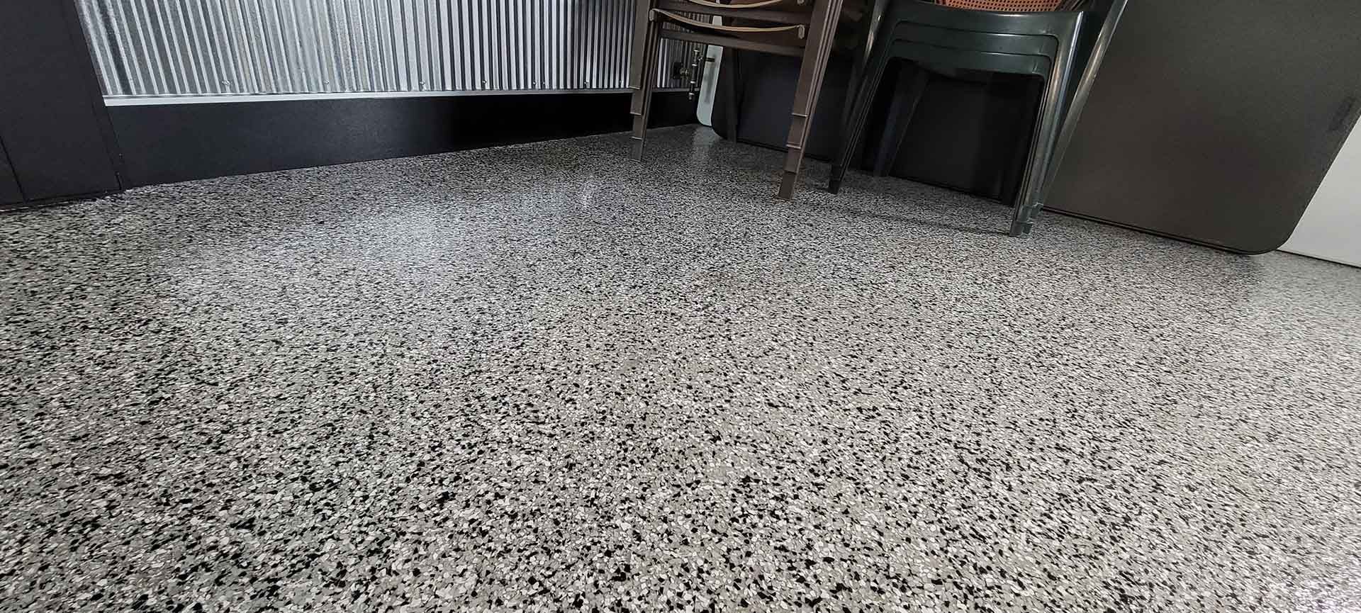Gray speckled carpet in a room with chairs and a table at the top edge