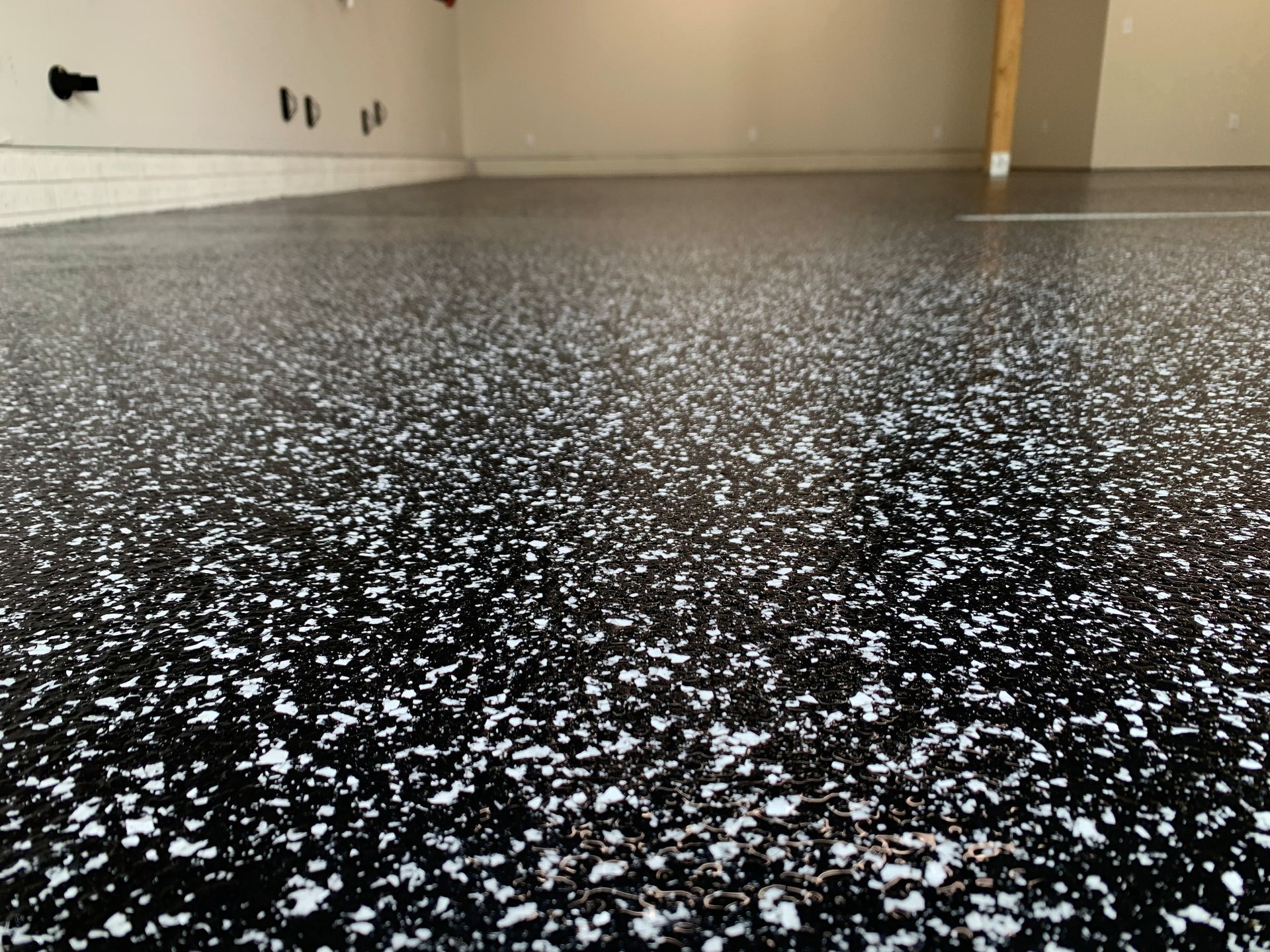 Speckled black epoxy floor in an empty room with white walls and baseboards