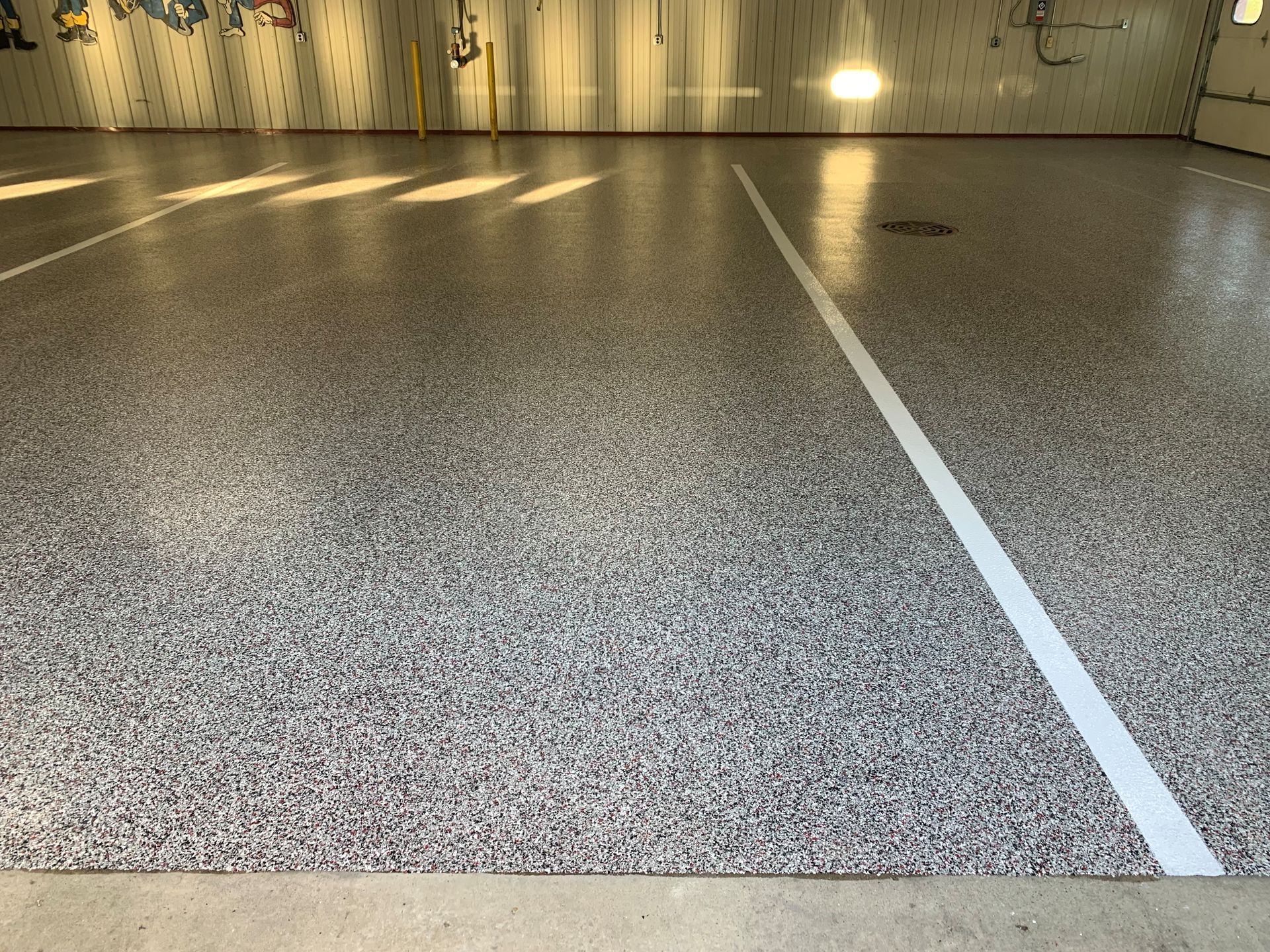 Empty indoor parking garage with speckled gray floor and white lane markings