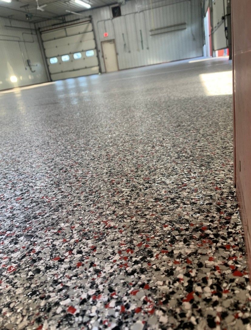 Speckled epoxy floor in an industrial garage with closed bay doors and bright overhead lights