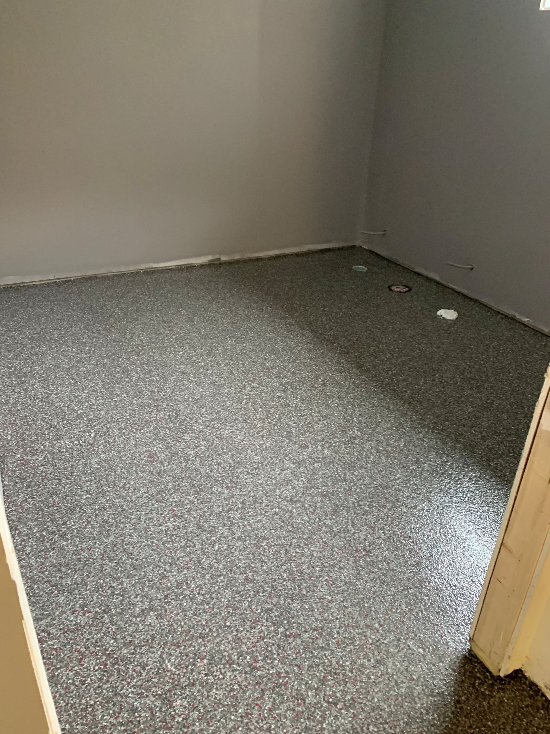 Empty carpeted closet with gray walls and a speckled gray floor