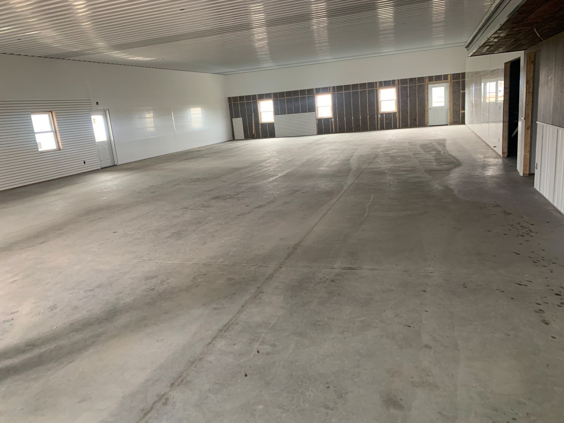 Large empty industrial room with a concrete floor and windows along the walls