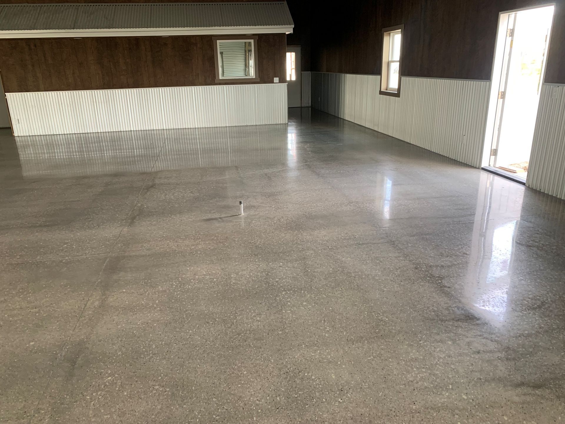 Empty garage with polished concrete floor and open doorway letting in daylight.
