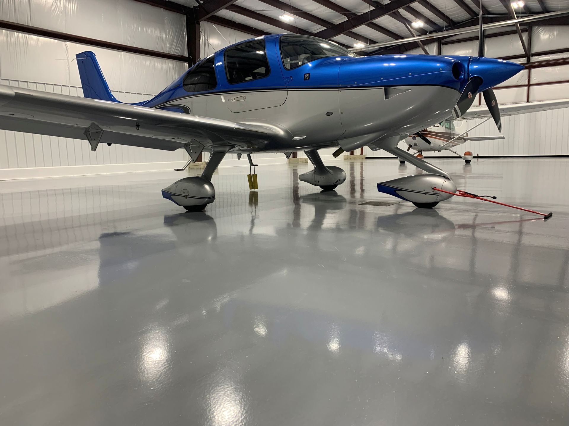 Blue-and-white single-engine airplane parked inside a hangar on a polished floor