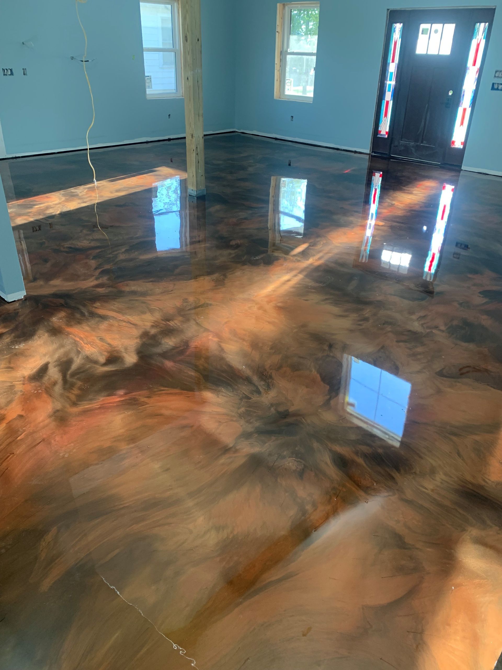 Shiny polished concrete floor in an empty room with blue walls and windows reflecting light