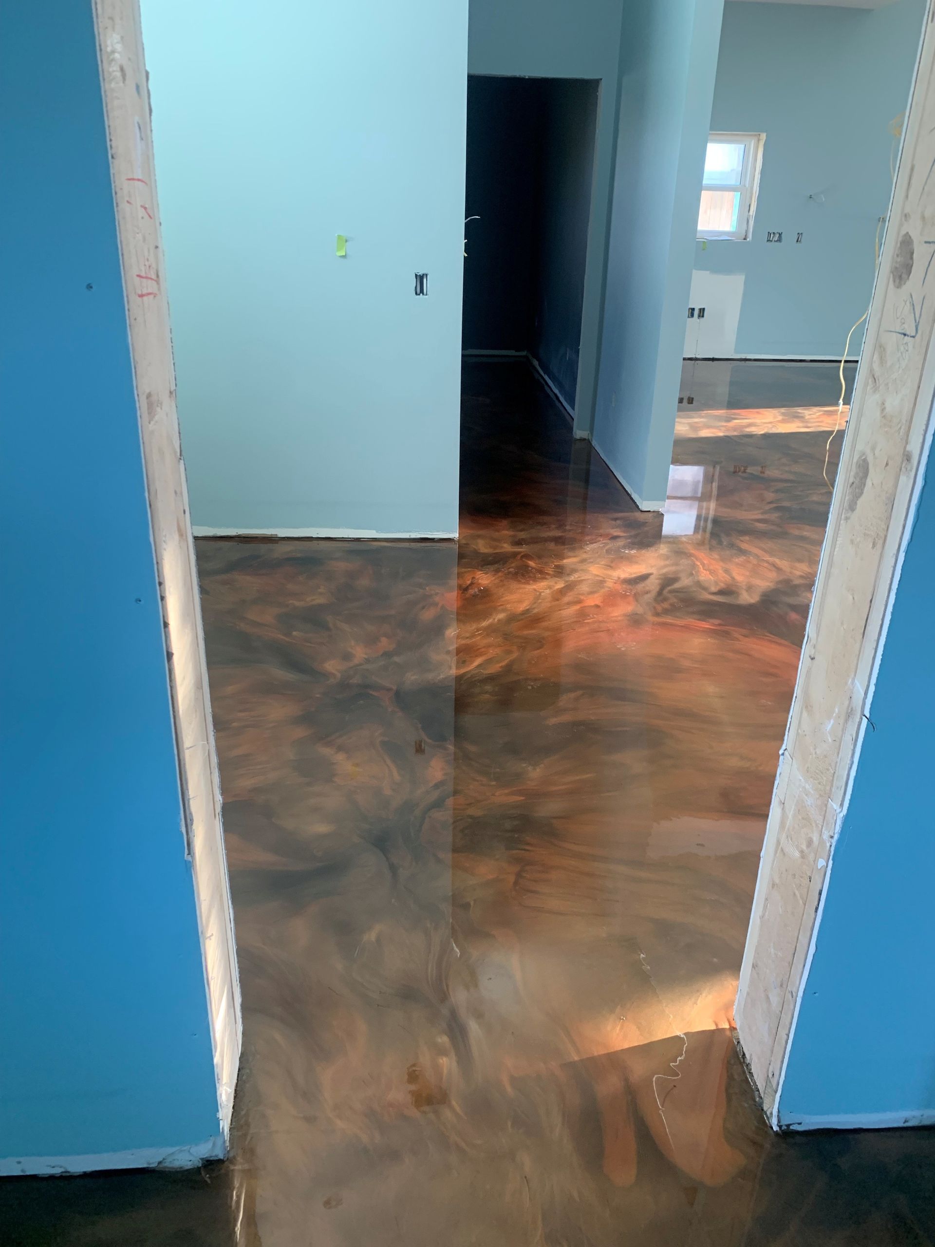 Empty hallway with blue walls, dark doorway, and glossy brown floor reflecting light.