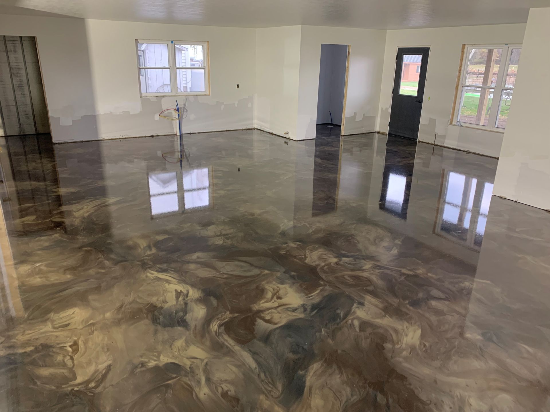 Empty room with glossy marbled floor and white walls, reflecting windows and doors.