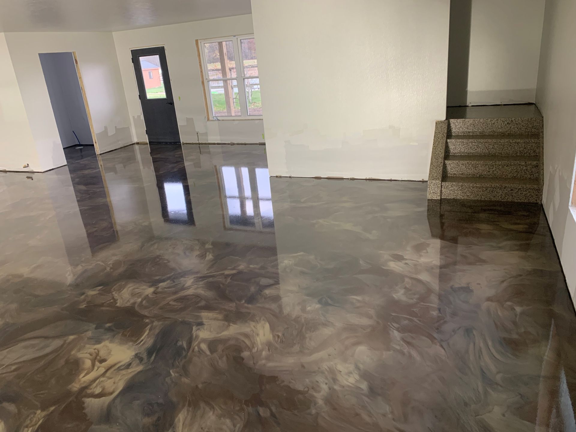 Empty room with glossy marbled floor, white walls, windows, and a staircase on the right