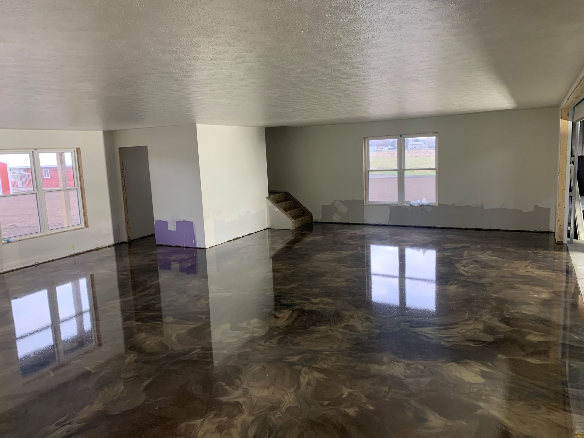Empty room with glossy dark marble floor, white walls, and large windows letting in daylight