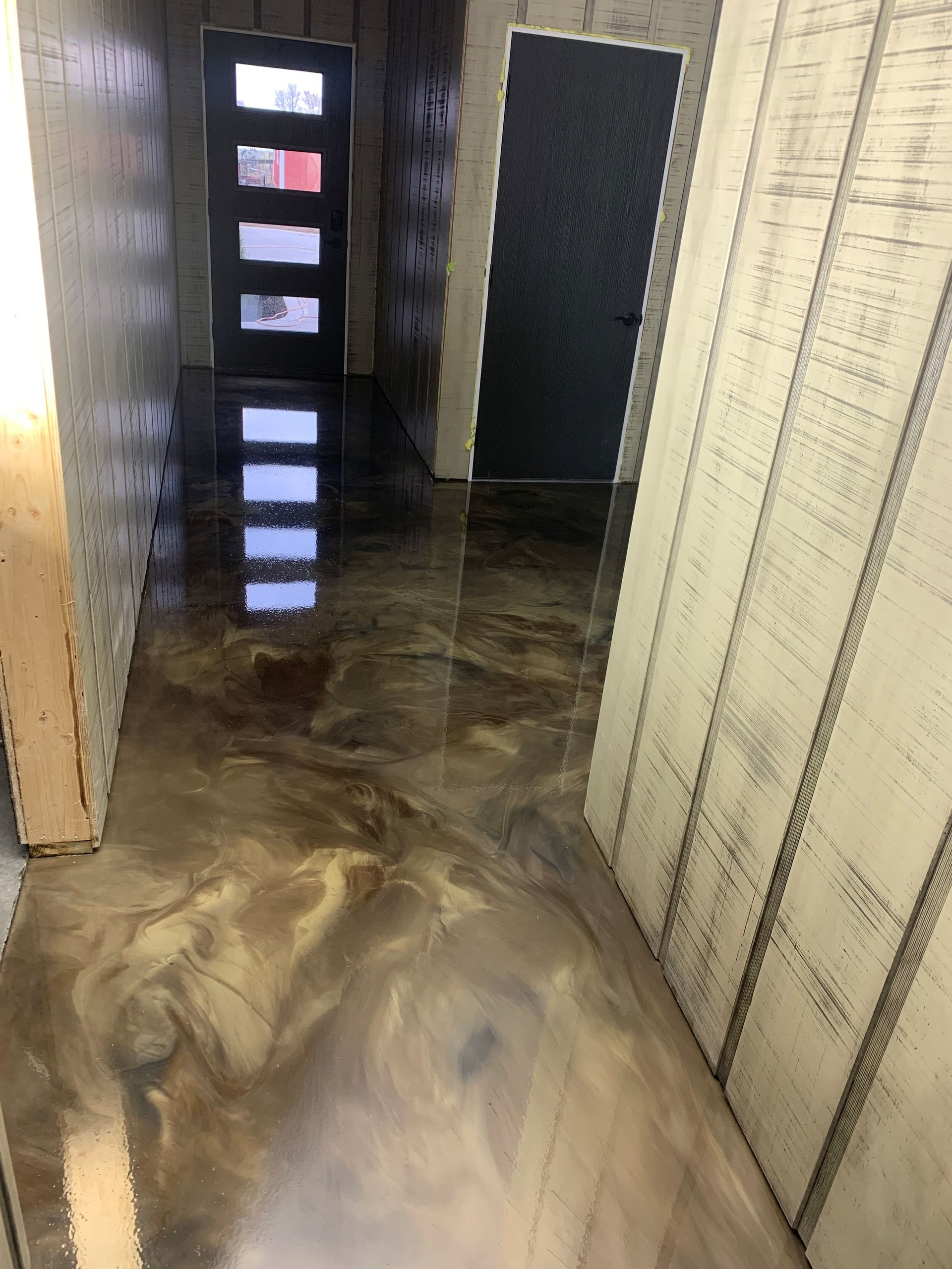 Flooded hallway with murky water and visible wall damage, leading to a doorway with light beyond
