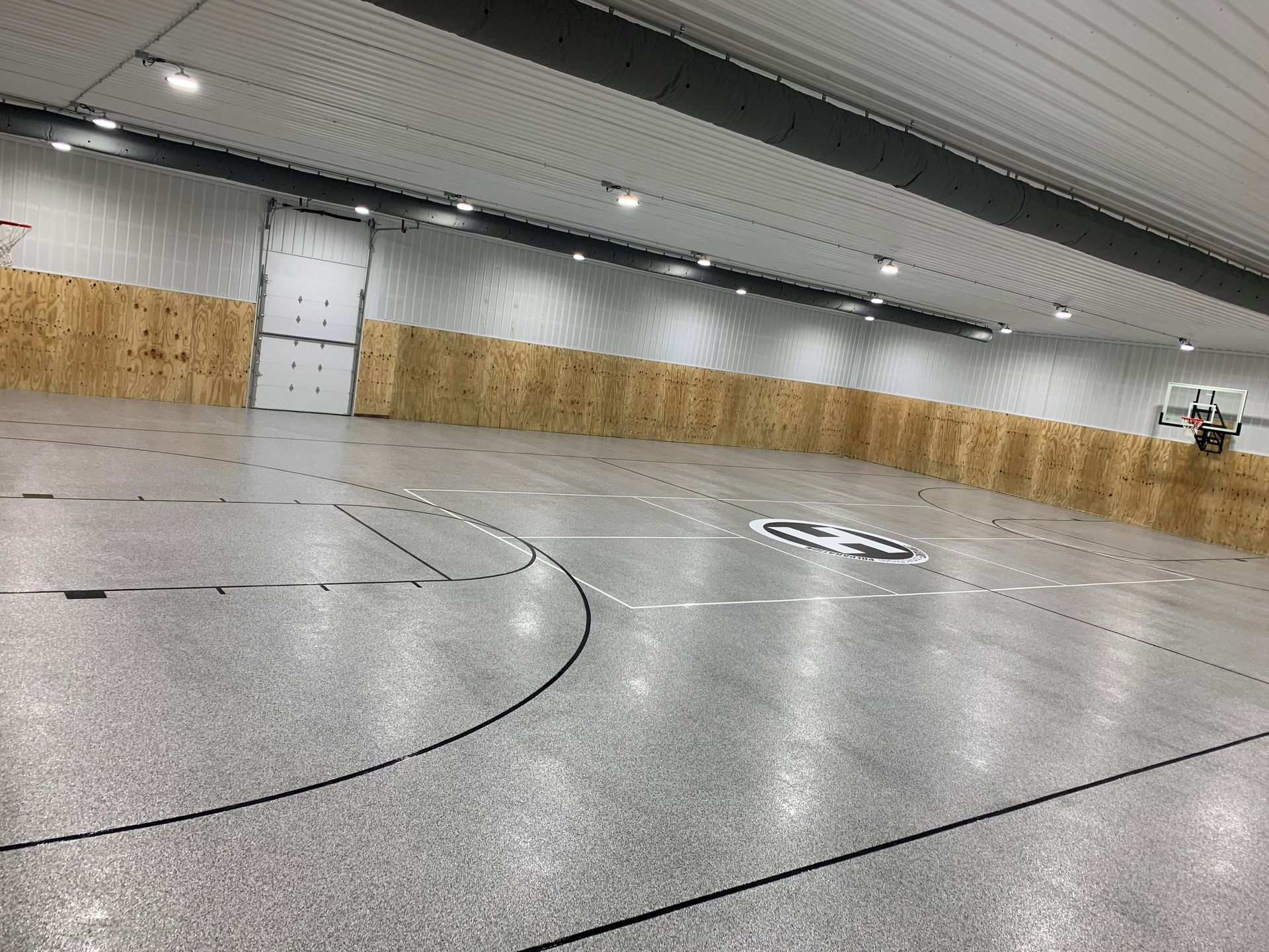 Indoor gym or arena floor with curved black lines and wood-paneled walls, seen at a slight tilt