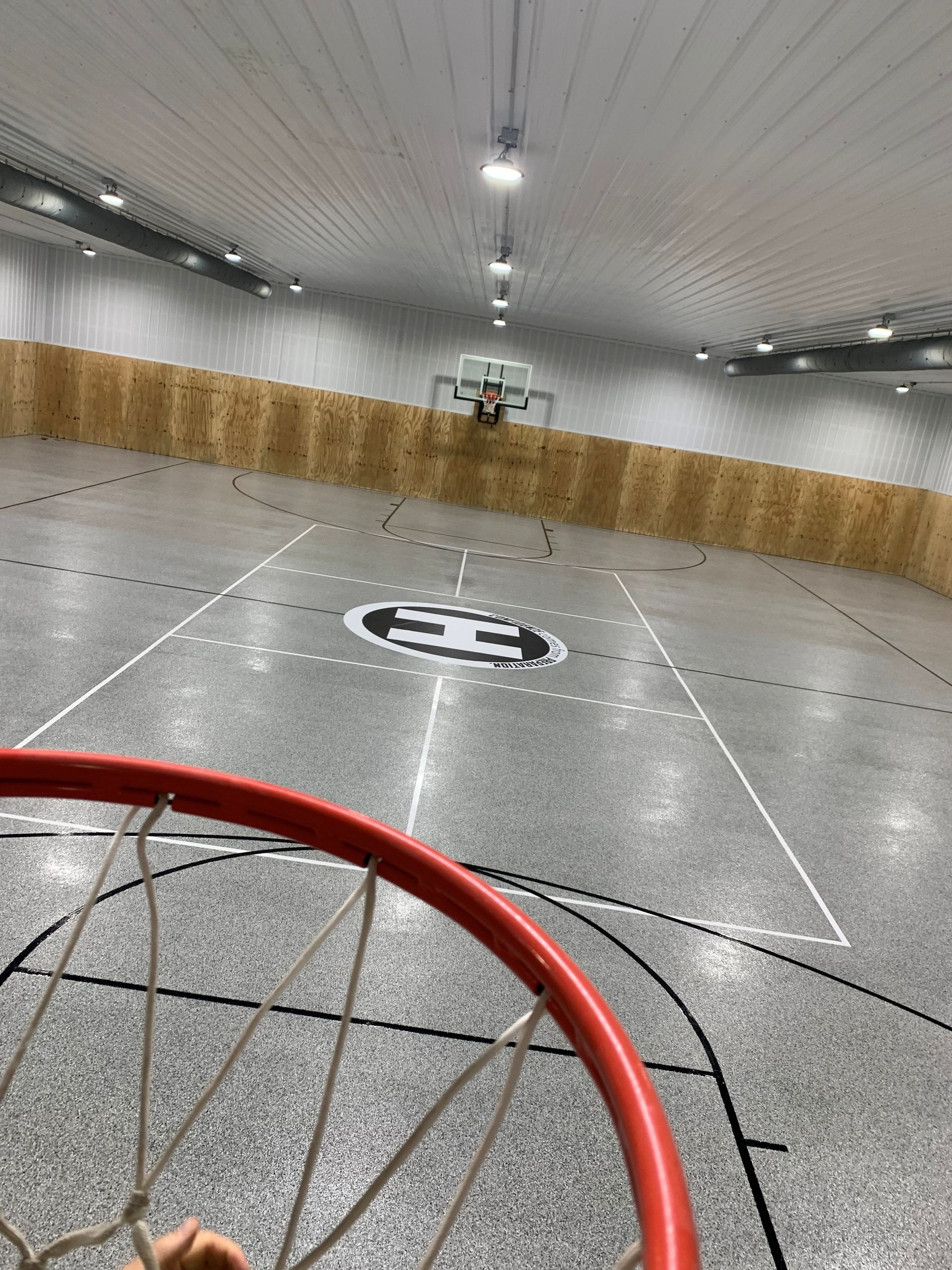 Indoor sports court with a red hoop in the foreground and a goal at the far end.