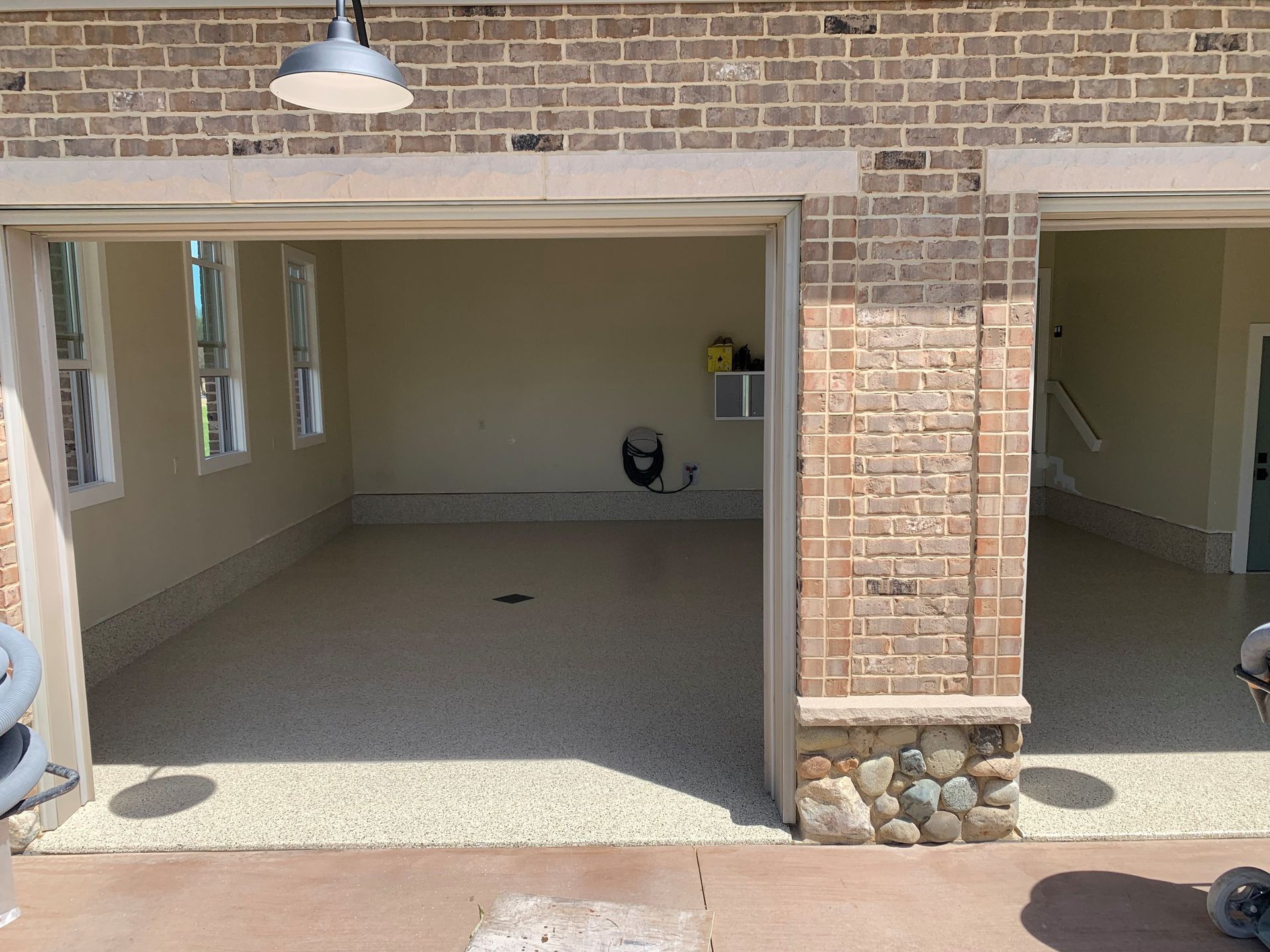 Brick patio with two open garage-style bays, stone floor, windows, and a hanging light