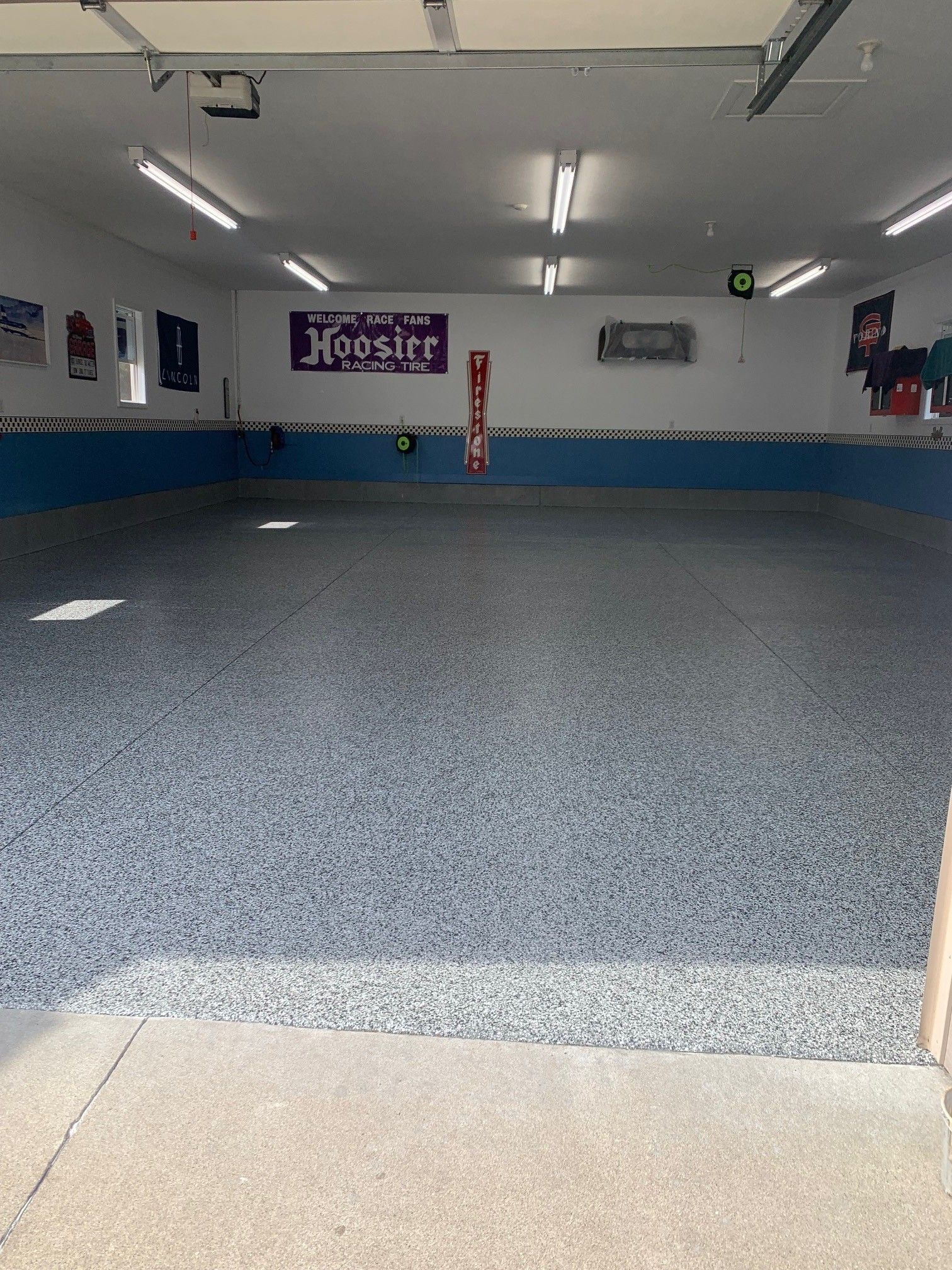 Empty indoor gym with blue flooring, white walls, and a banner on the far wall.