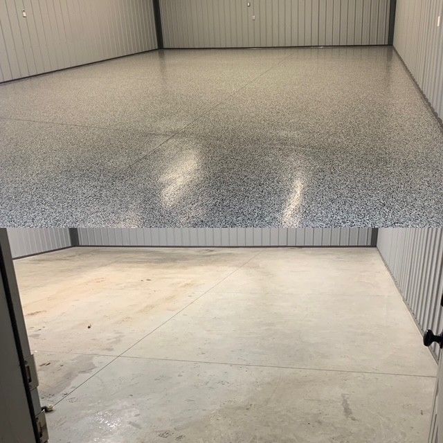 Empty storage unit with a speckled gray epoxy floor and beige concrete floor visible through the open doorway