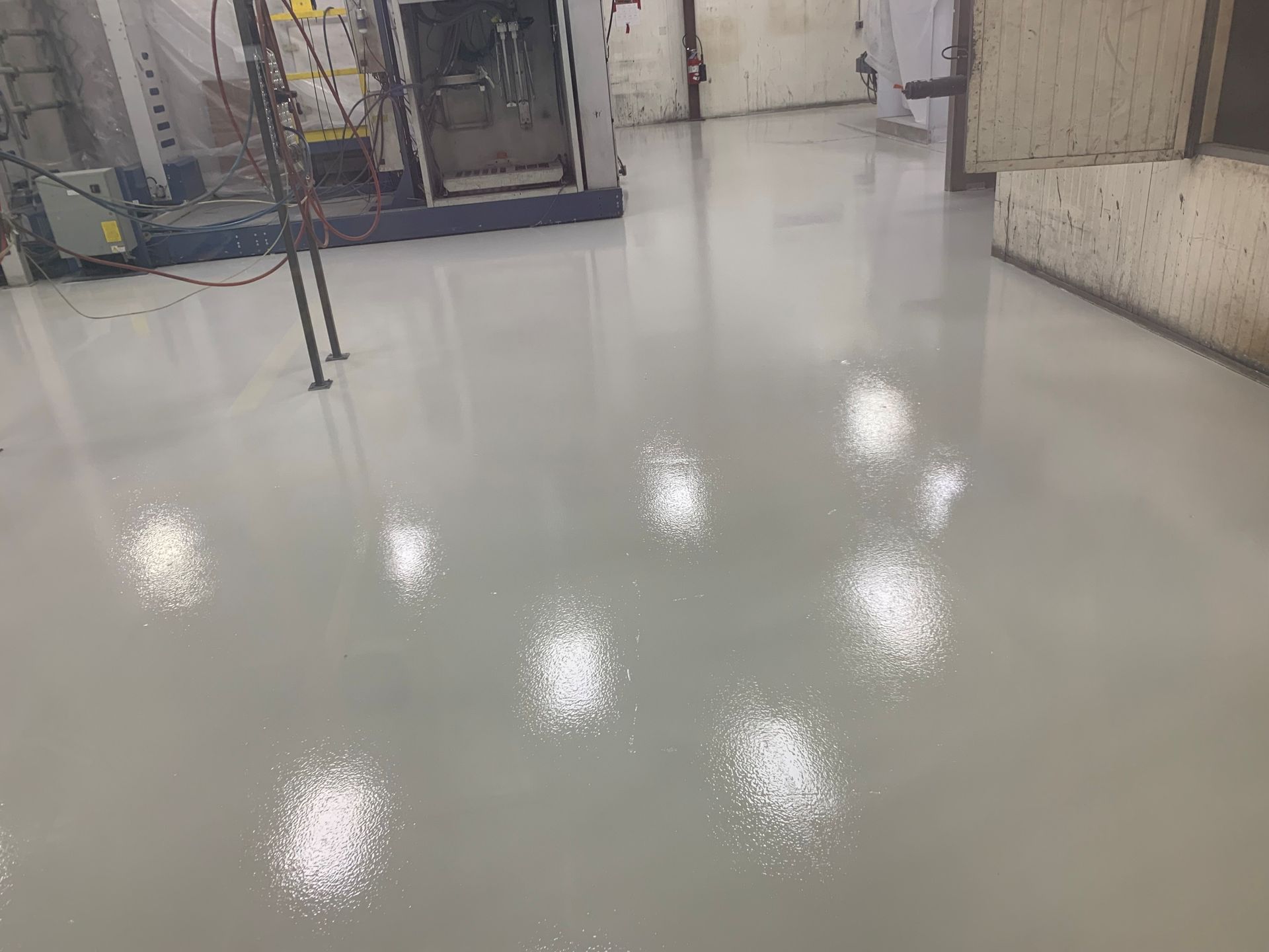 Empty glossy white floor in an indoor industrial hallway with bright ceiling light reflections