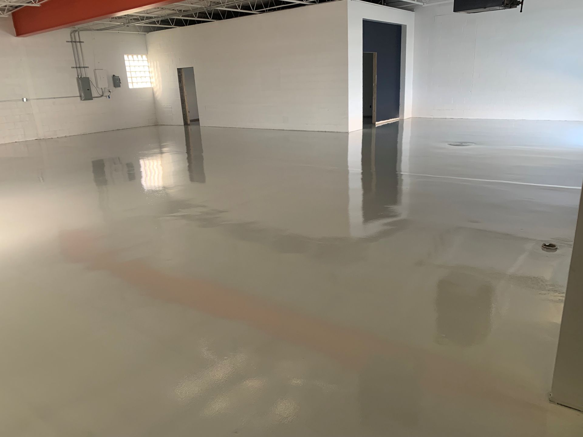 Empty room with a glossy flooded floor, white walls, and an open doorway.