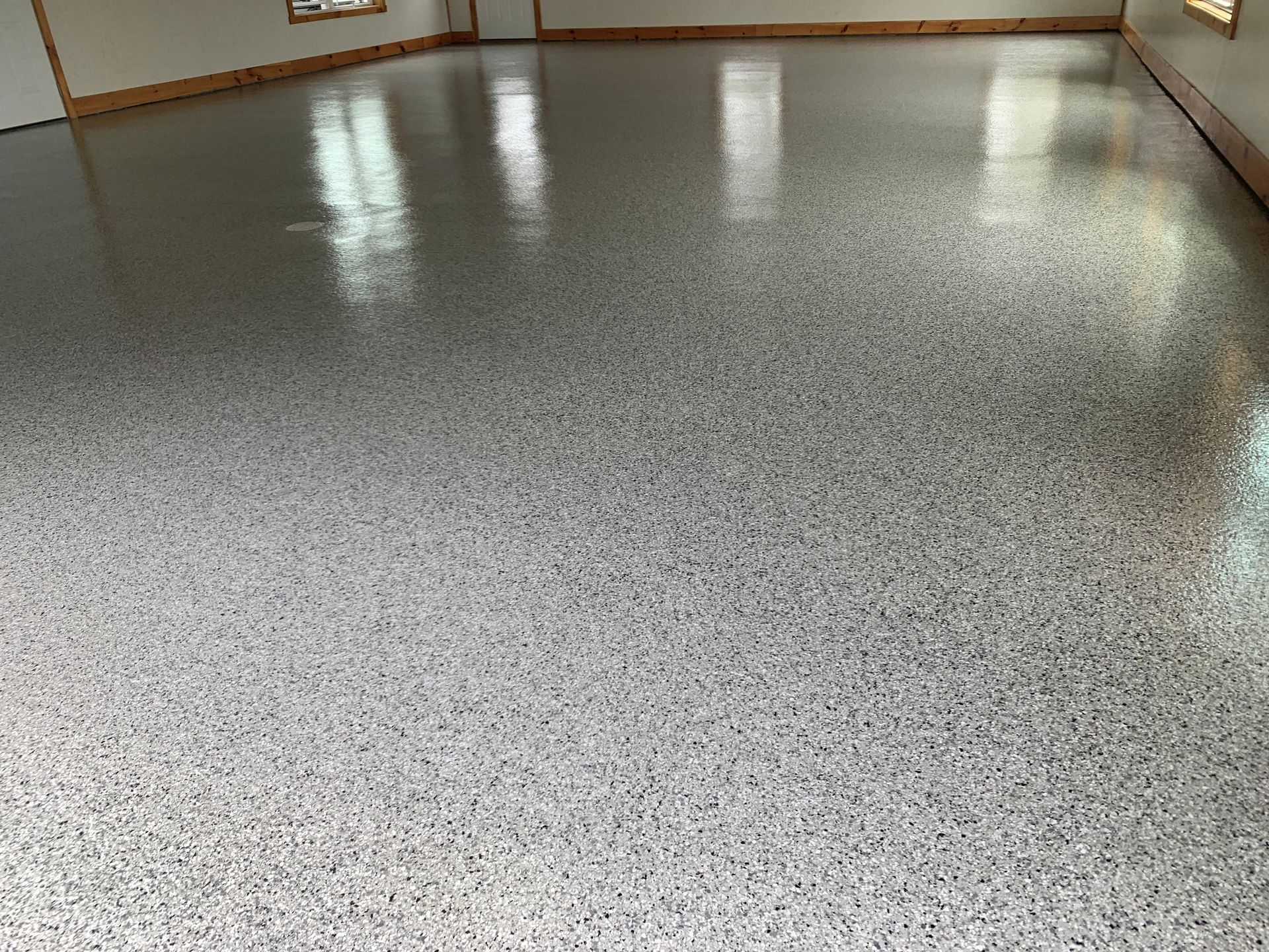 Shiny speckled gray floor in an empty room with wood-trimmed walls