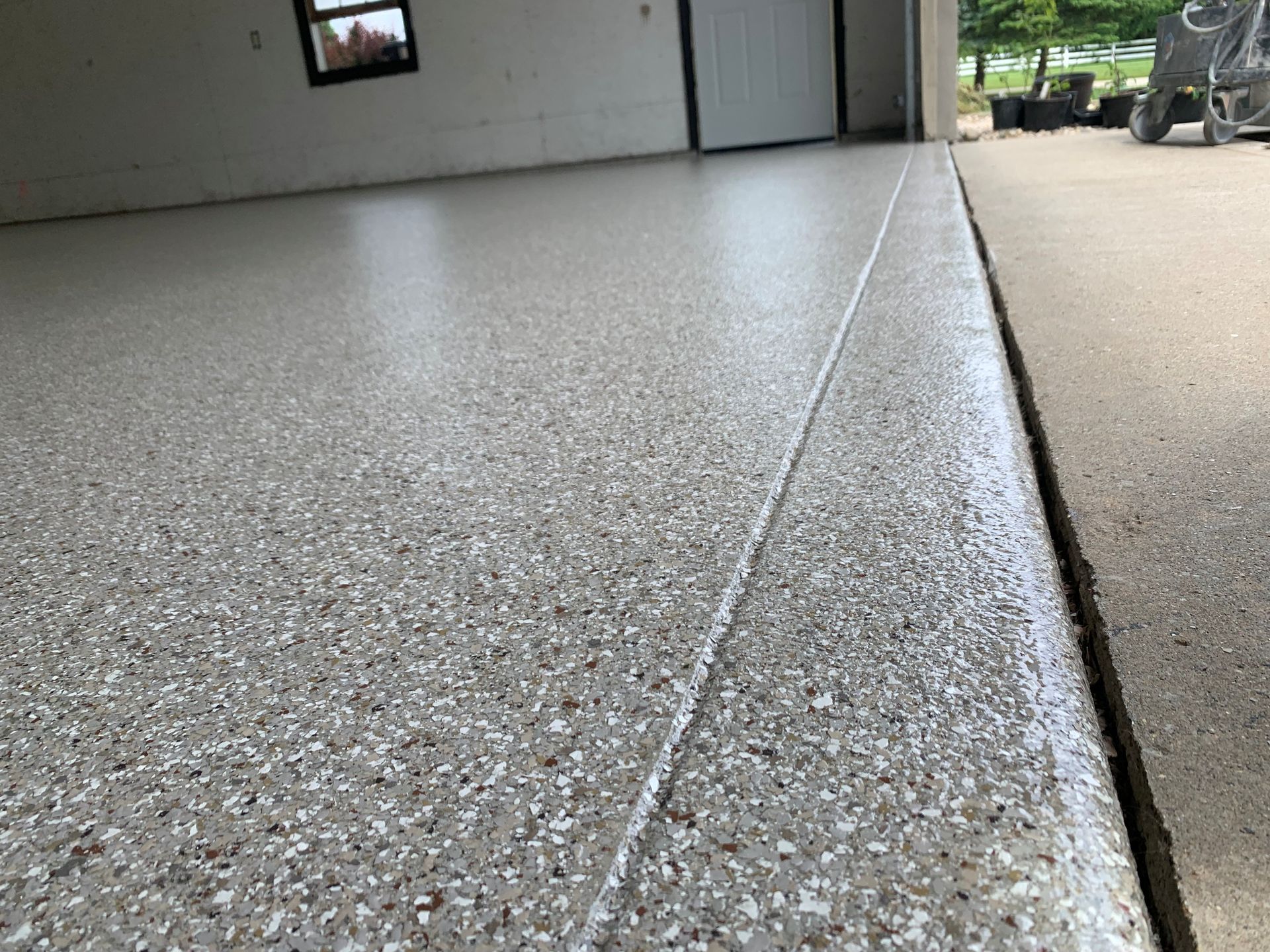 Textured concrete garage floor beside a smooth driveway, viewed from a low angle