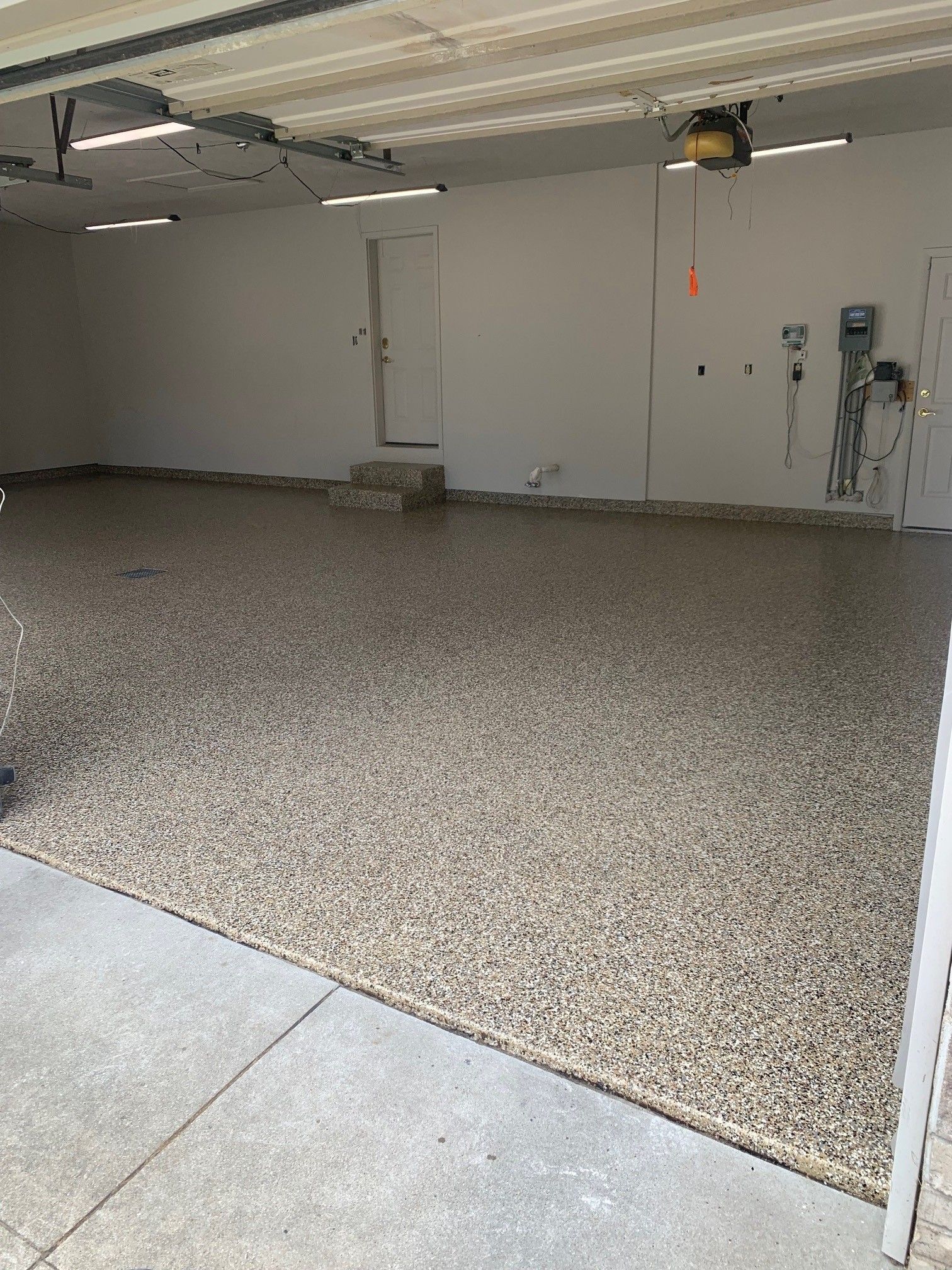 Empty garage with a speckled epoxy floor and concrete apron, viewed from the open doorway
