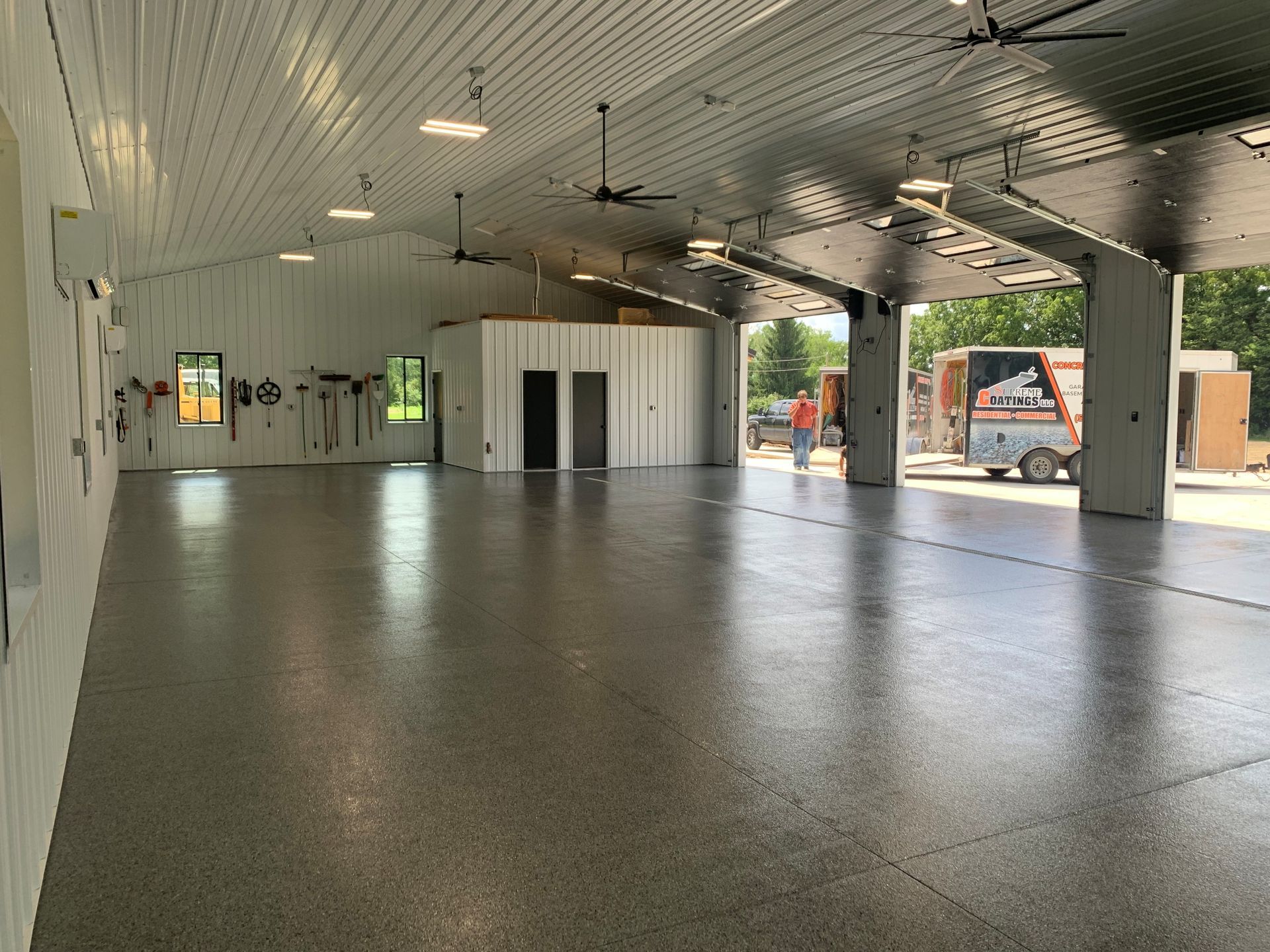 Empty modern parking garage with concrete floor, white ceiling, and open sides showing outside light