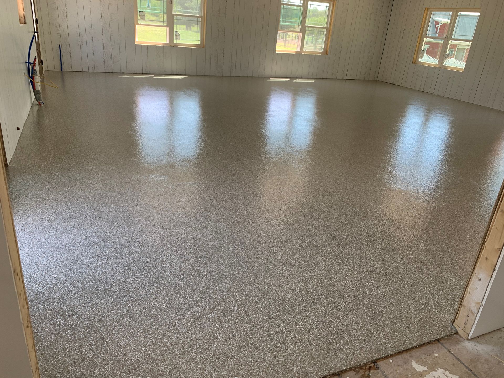 Empty speckled floor in a bright room with windows and beige walls