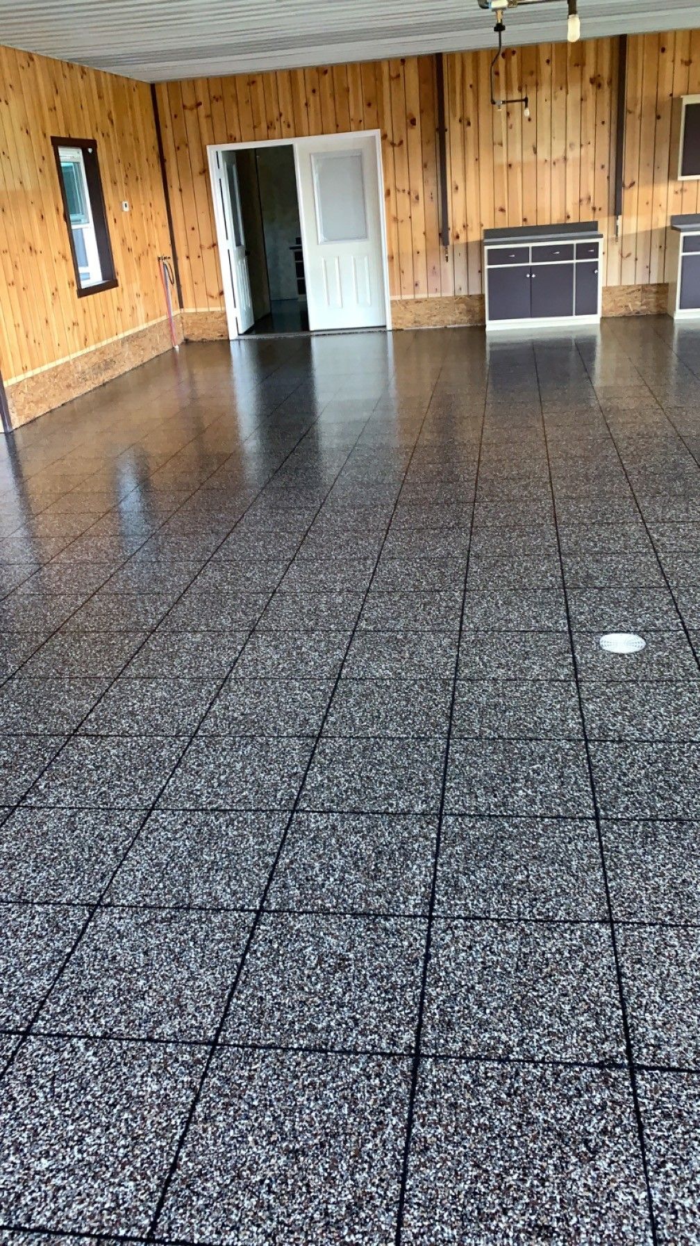 Empty wood-paneled room with speckled tile floor and an open doorway