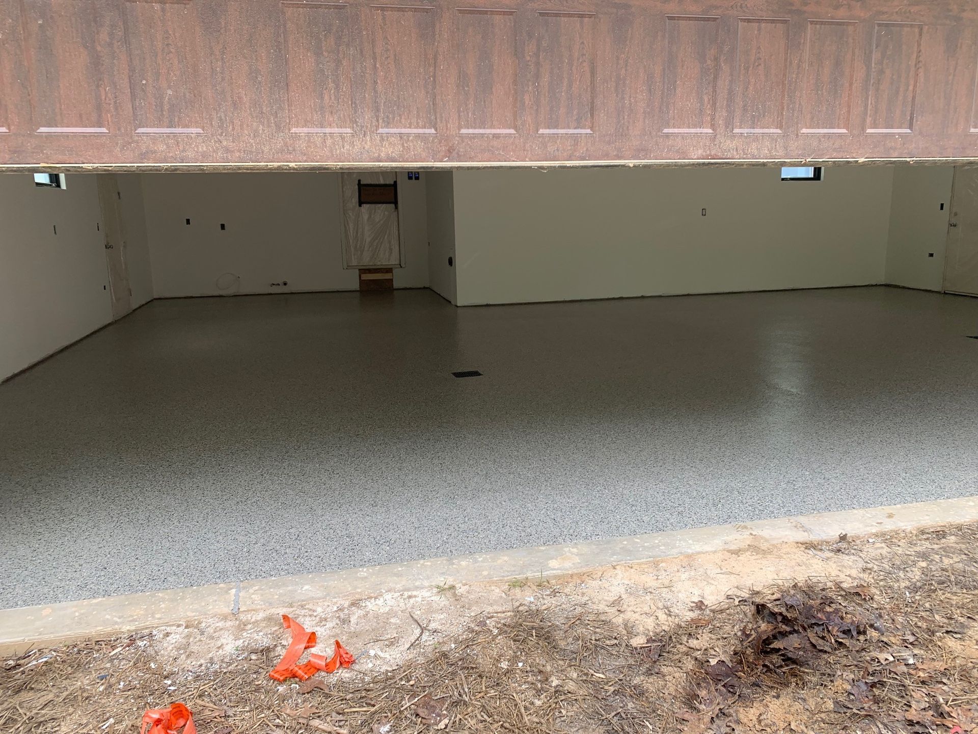 Wide view of an empty garage with a concrete floor and open door at the front.