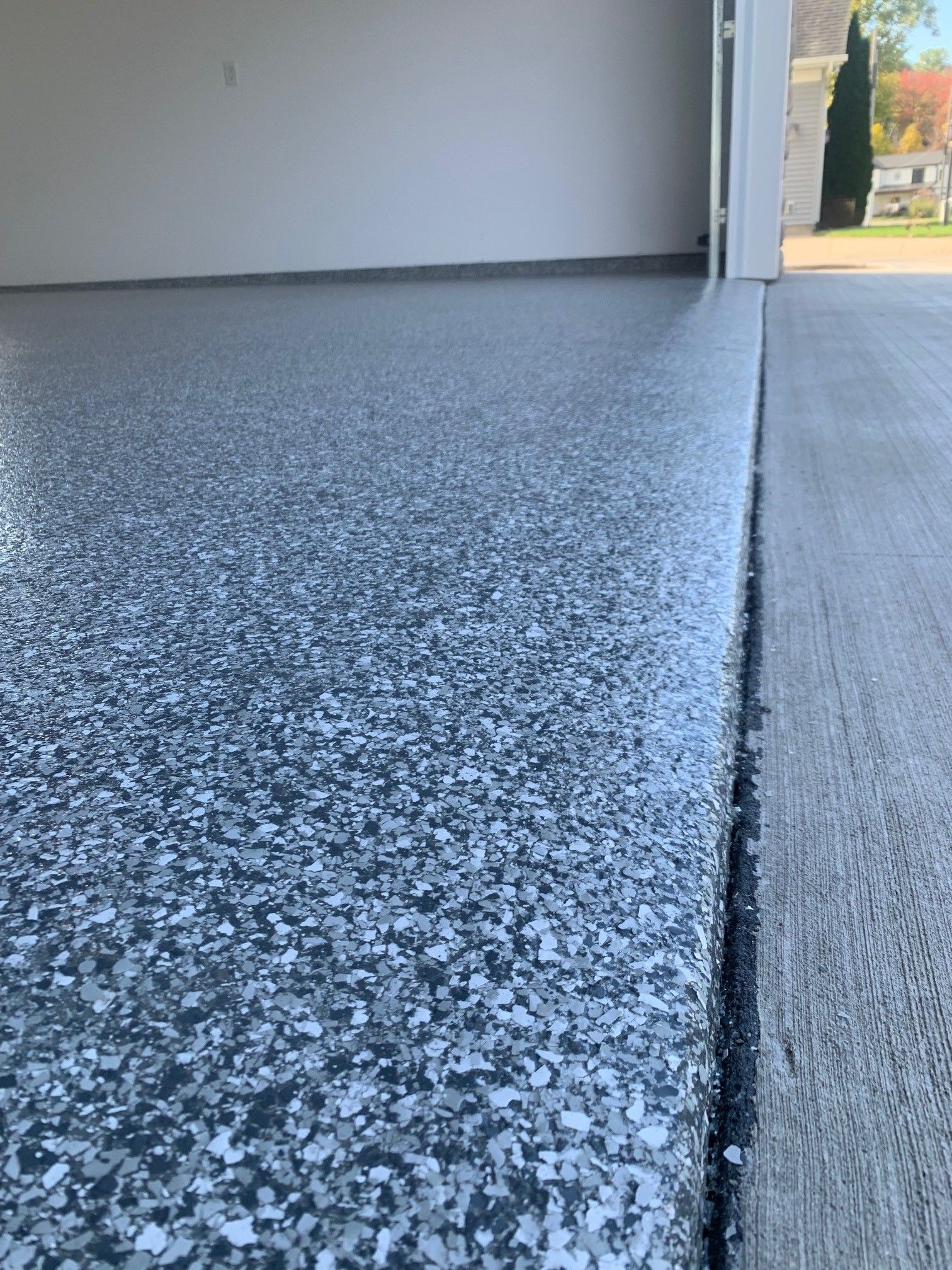 Speckled epoxy garage floor with an open doorway to the outside