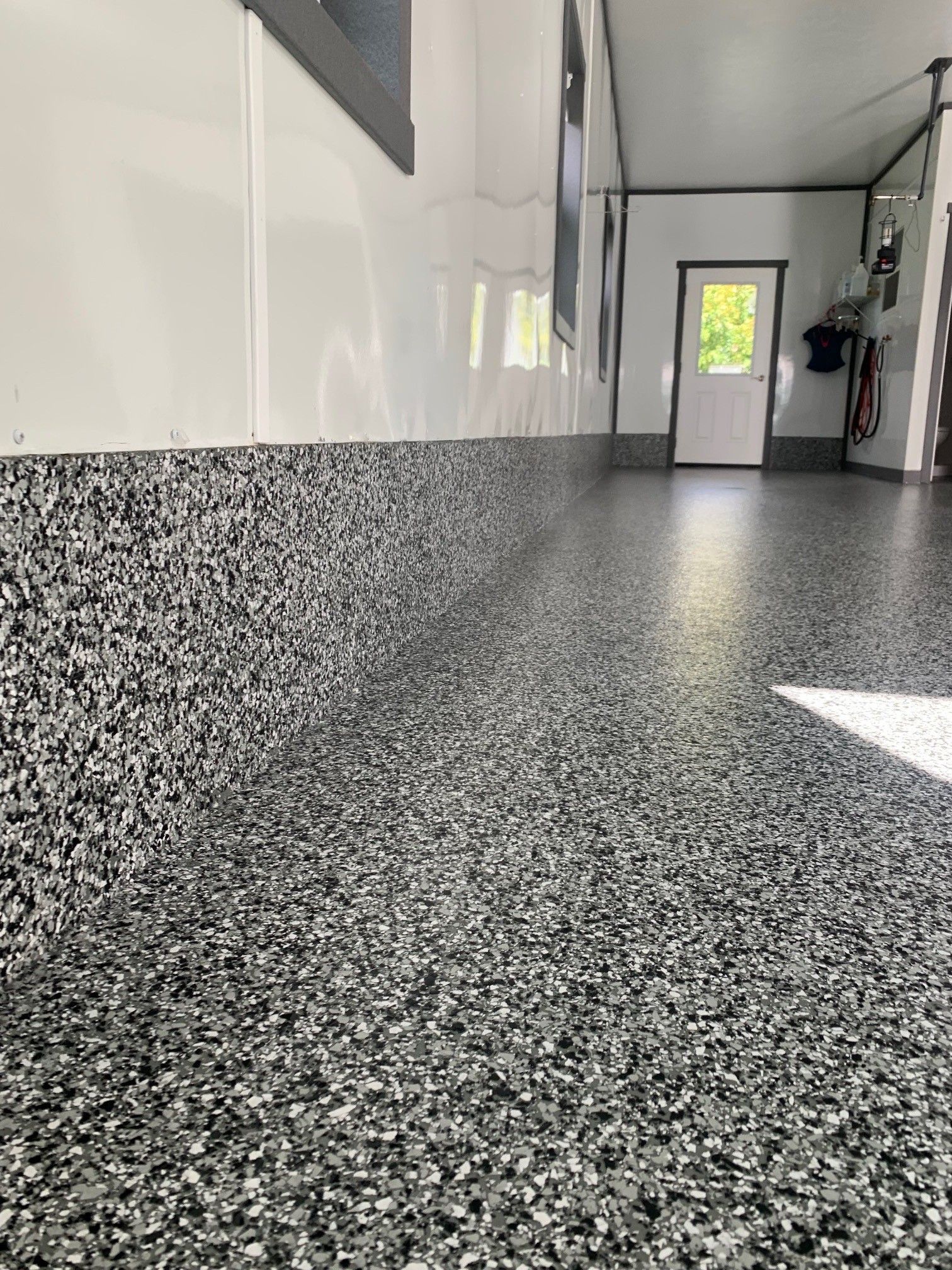 Speckled gray floor in a bright hallway with white walls and a door at the end