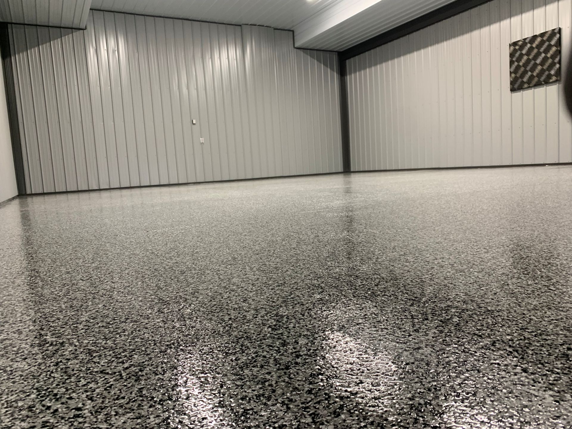Empty speckled garage interior with closed white paneled doors and a low ceiling