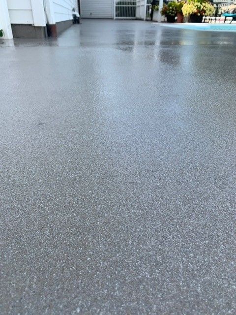 Rain-slick gray pavement in an outdoor plaza, with a few blurred people and buildings in the distance