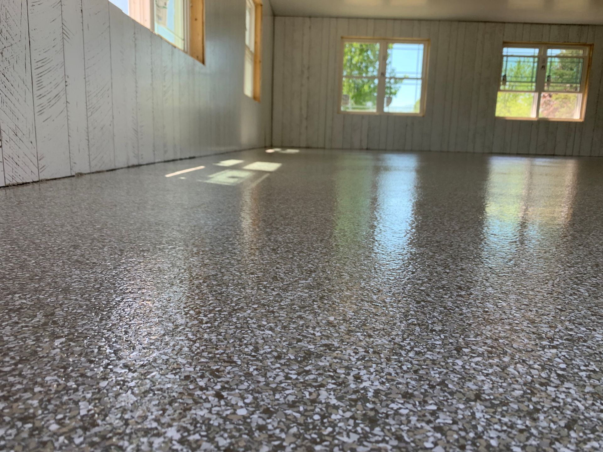 Empty room with speckled polished floor and sunlight from windows