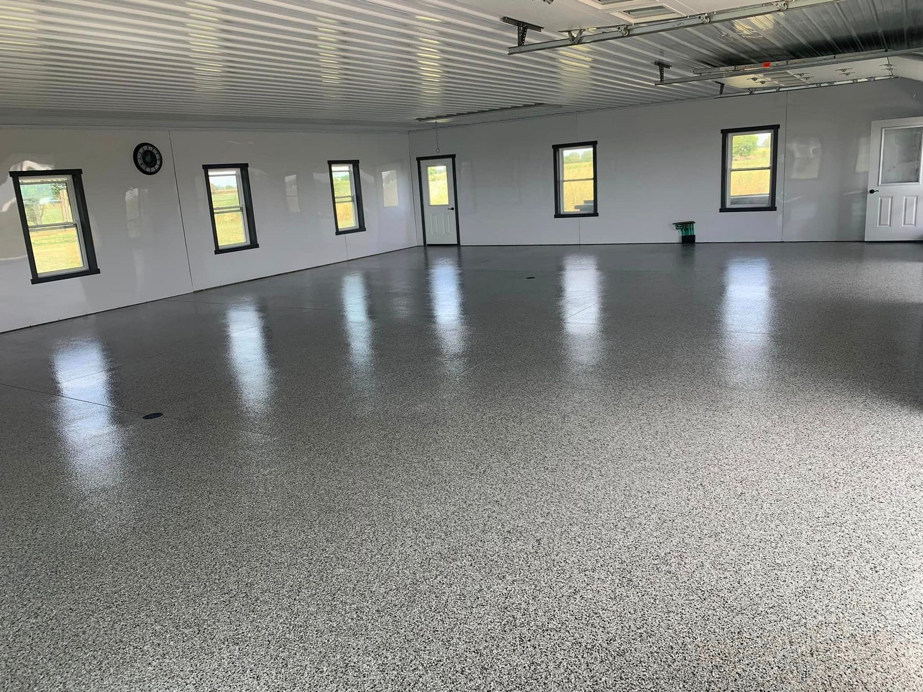 Empty room with speckled gray floor, white walls, and several small windows letting in daylight
