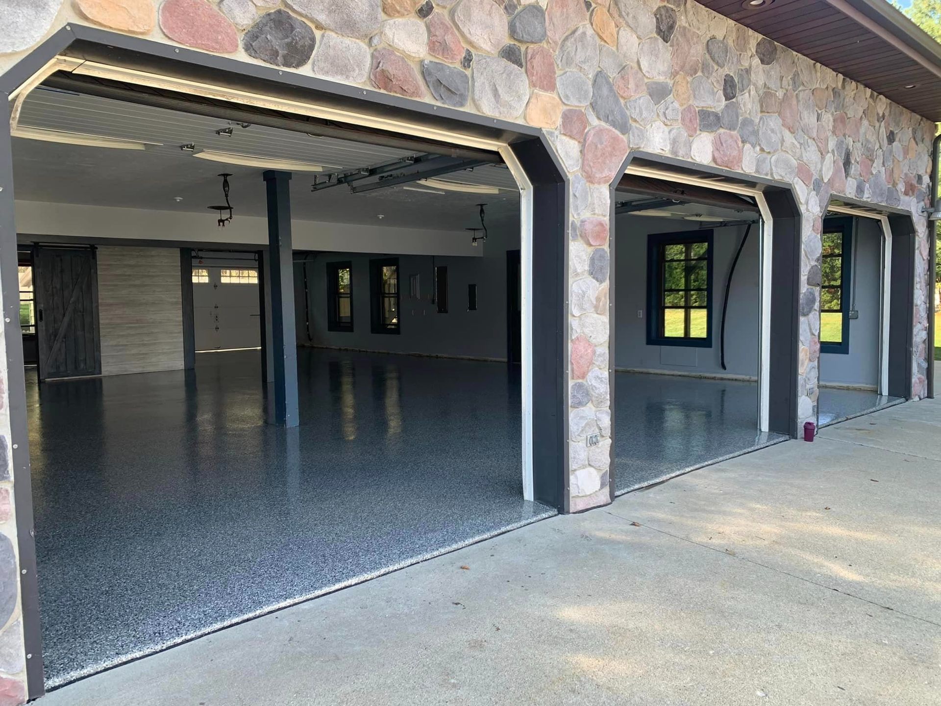 Open garage with stone exterior and a polished concrete floor, looking into an empty interior space.