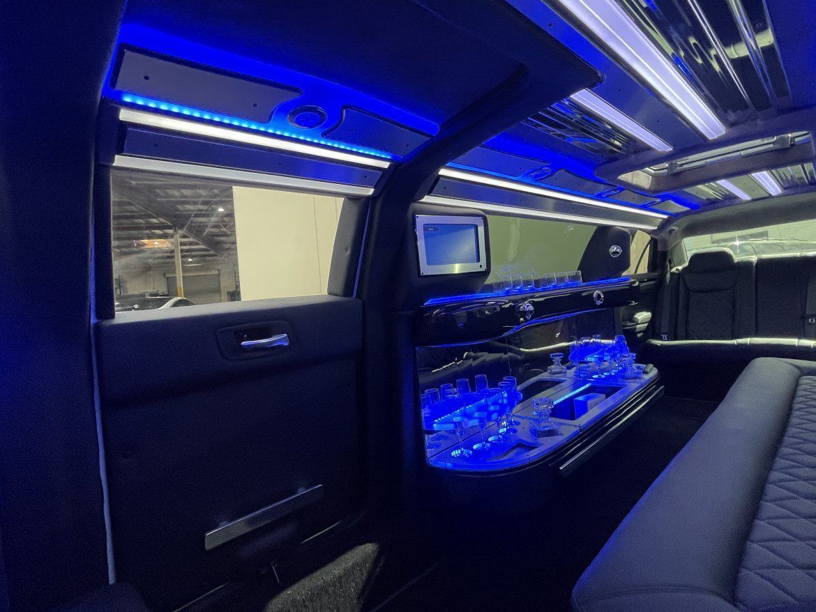Interior of a limousine with blue neon lights. The bar area has blue LED lighting and a small TV.