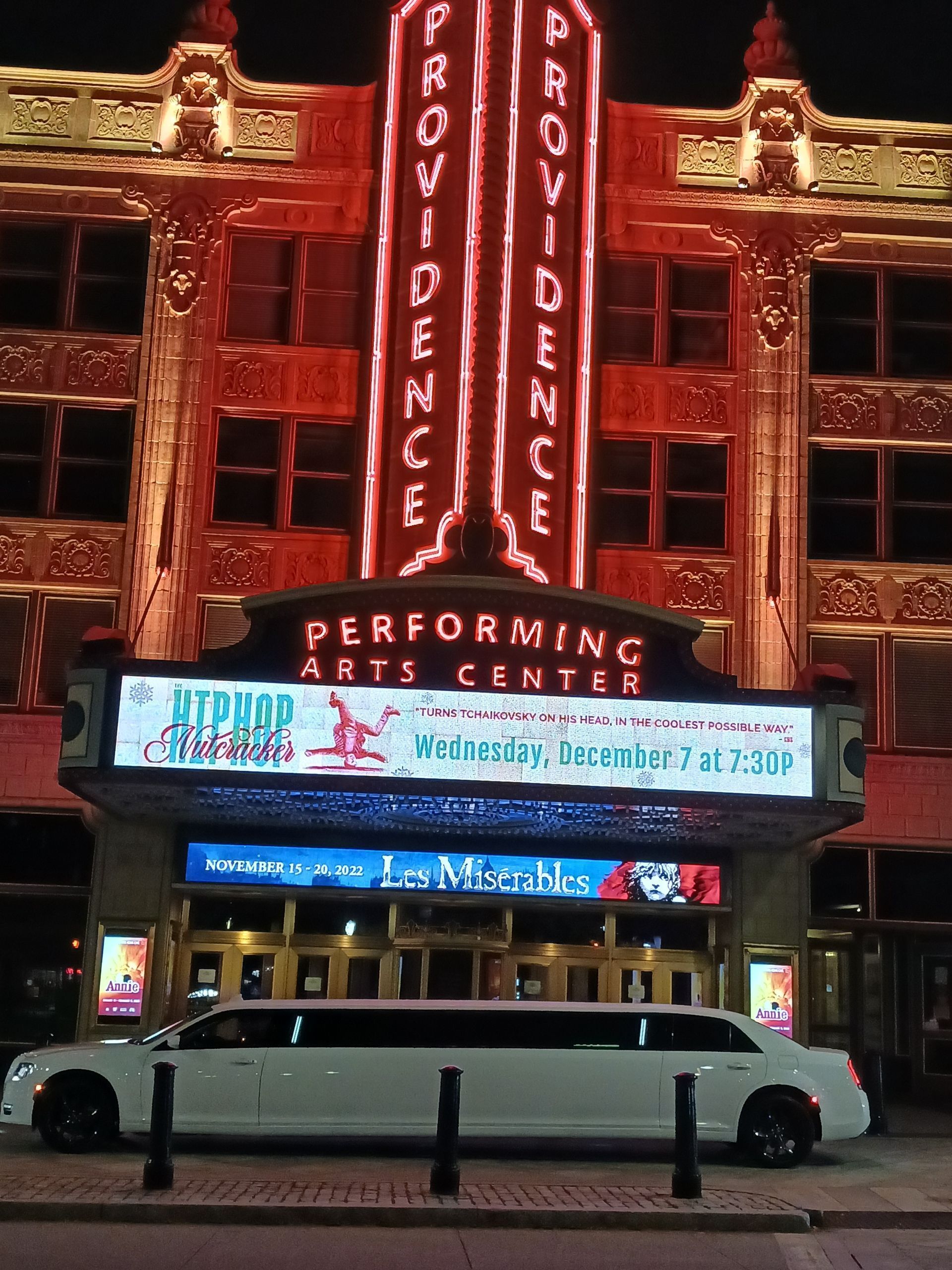 Providence Performing Arts Center at night with a white limousine parked in front. Neon sign.